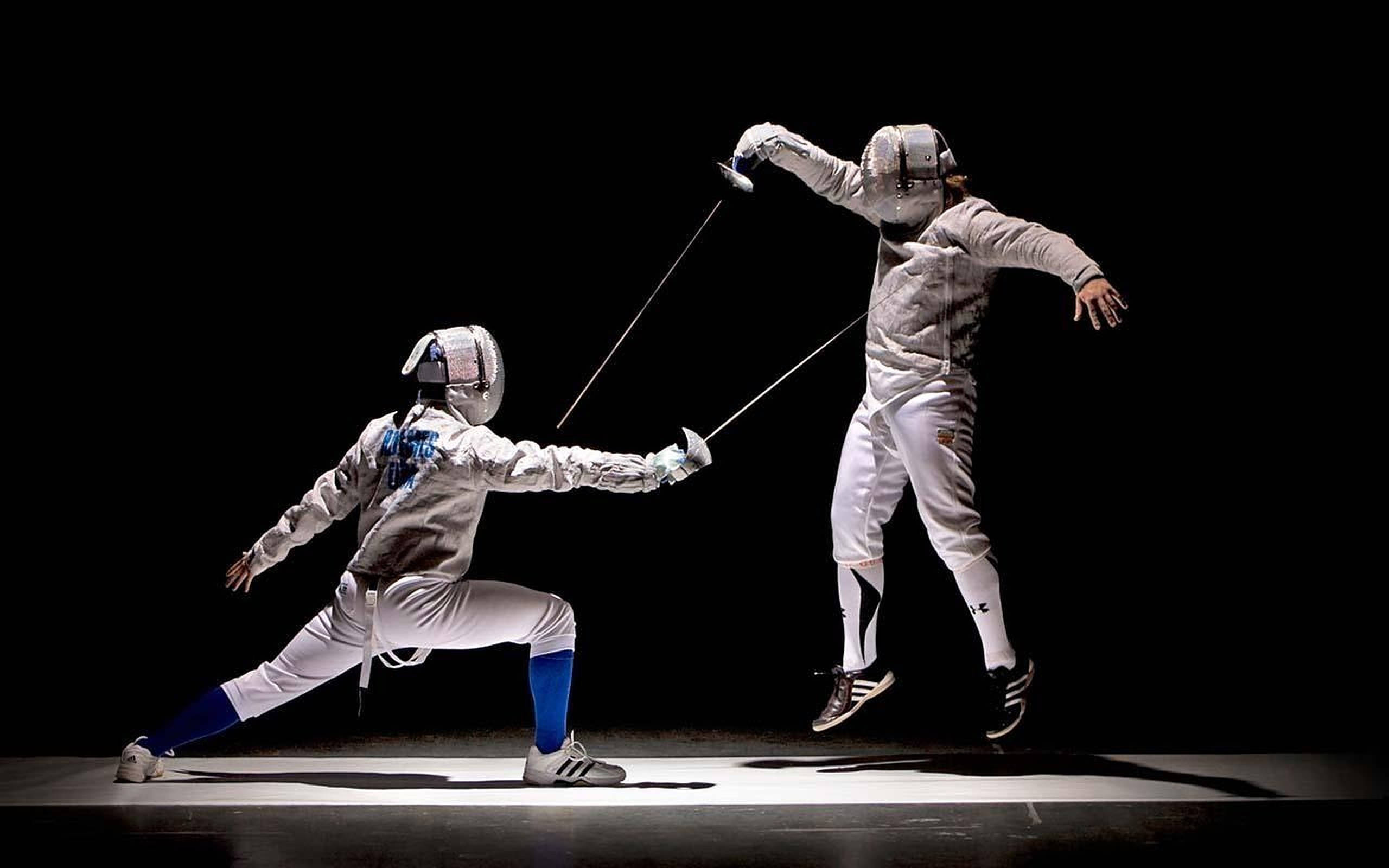 Fencing 桌布 壁紙 — 兩名身穿白色裝備的劍擊手在黑色背景的戲劇性聚光燈下交鋒。
