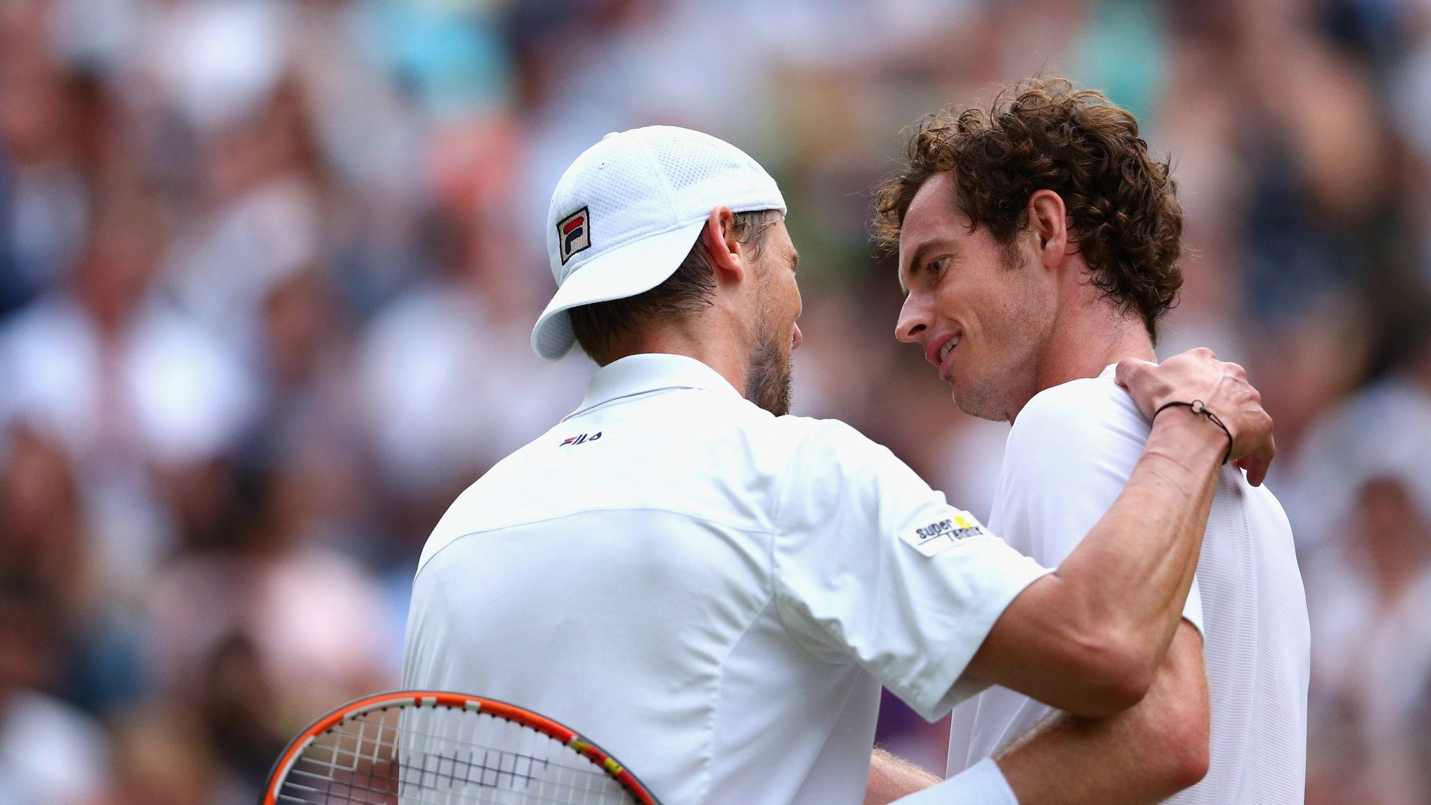 Tennis 桌布 壁紙 — 兩名身穿白色裝備的網球選手在陽光明媚的草地上熱情擁抱，身後是模糊的觀眾。