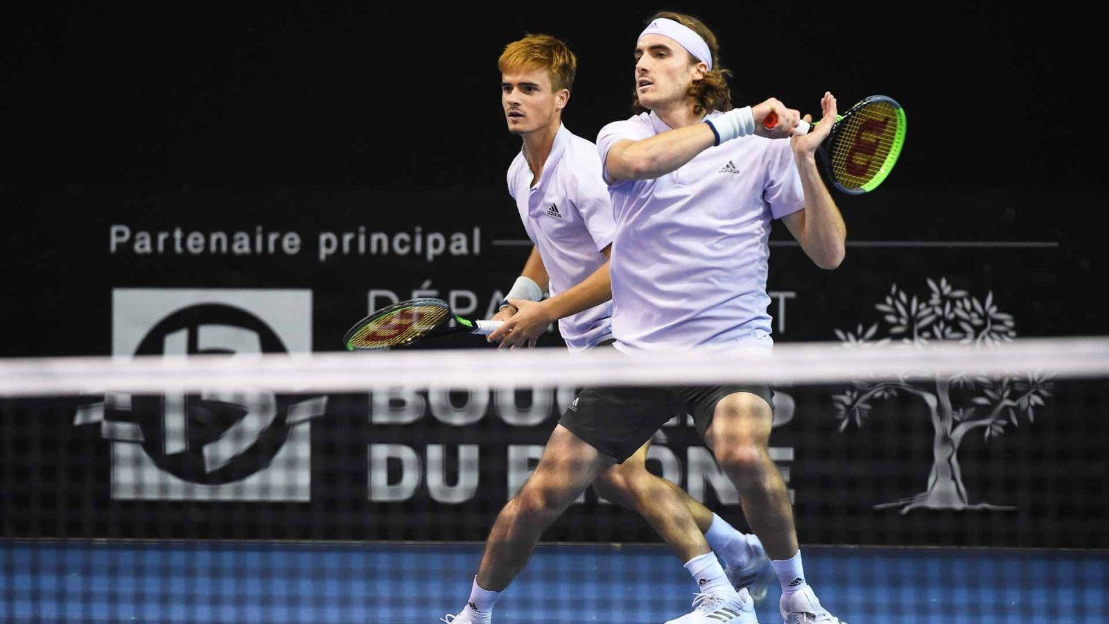 Tennis 桌布 壁紙 — 兩名身穿白色襯衫的男性網球選手在明亮的體育場燈光下於雙打比賽中激烈競爭。