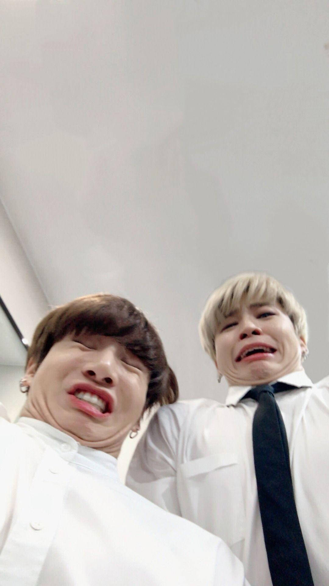 Jikook 桌布 壁紙 — 兩名身穿白襯衫的年輕男子在普通天花板背景下，為近距離自拍做出誇張的傻臉。