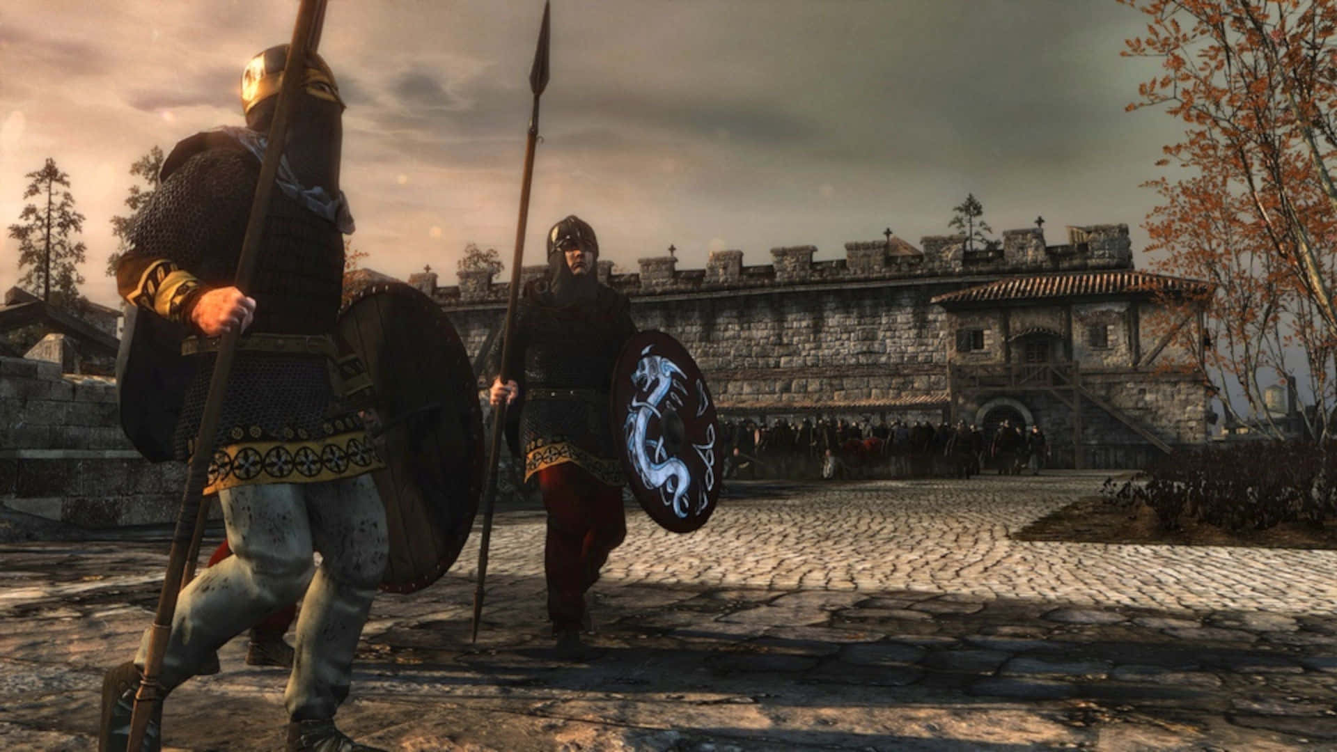 Total War Attila 桌布 壁紙 — 兩名身穿盔甲的中世紀戰士，在陰天下一座石城堡前的鵝卵石路上，手持長矛和盾牌向前行進。