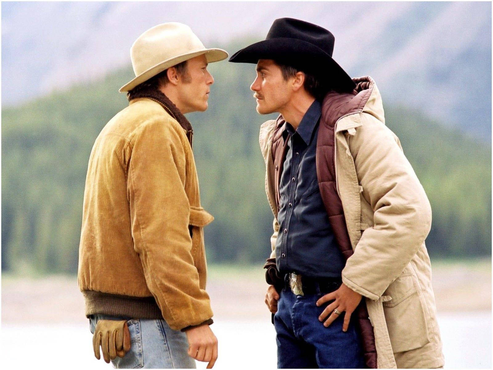 brokeback mountain 桌布 壁紙 — 兩名身穿粗獷外套的牛仔在迷霧山巒和森林背景下緊張對峙。