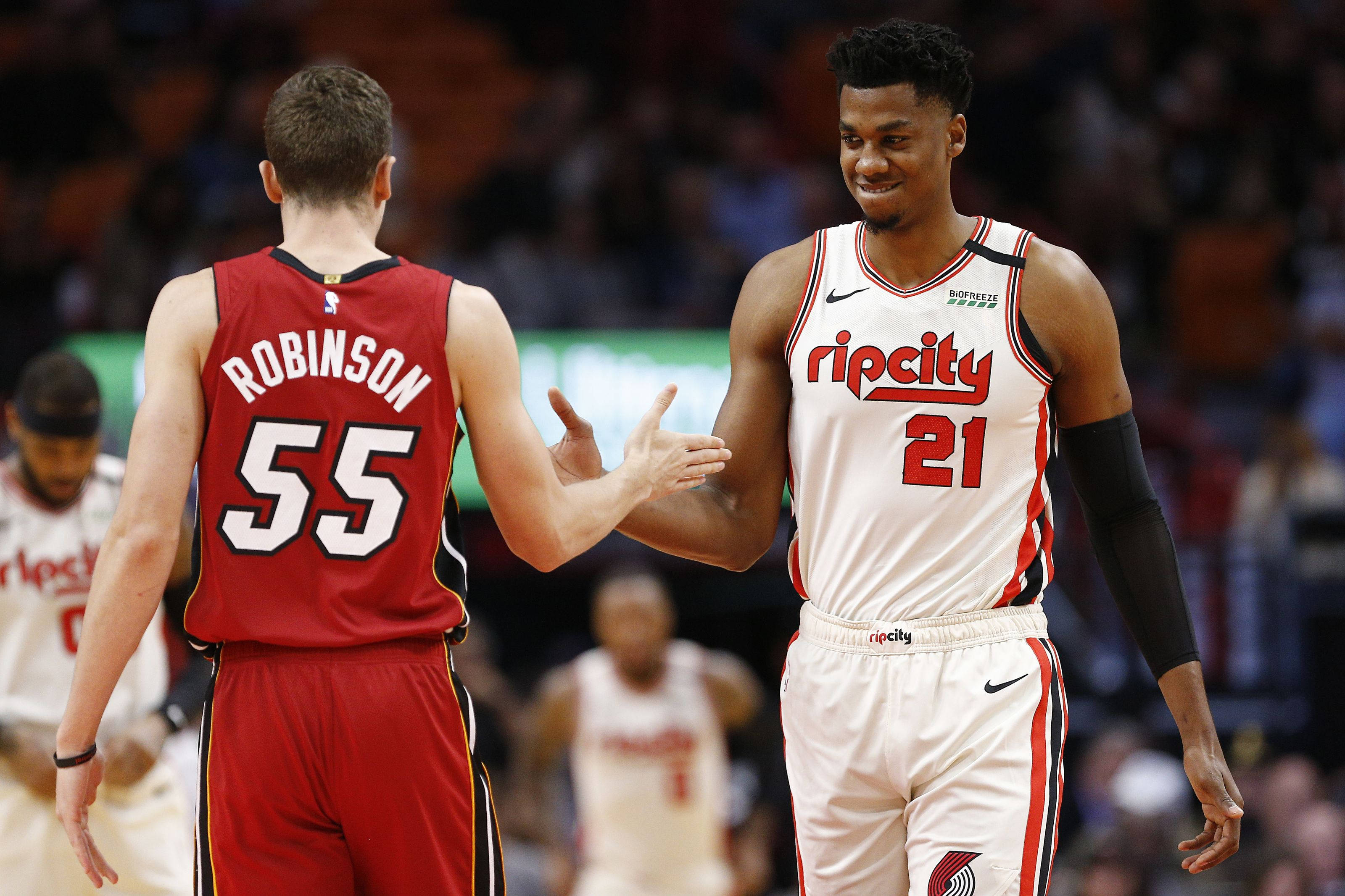 duncan robinson 桌布 壁紙 — 兩名身穿紅白球衣的籃球運動員在球場上握手，背景是模糊的觀眾。
