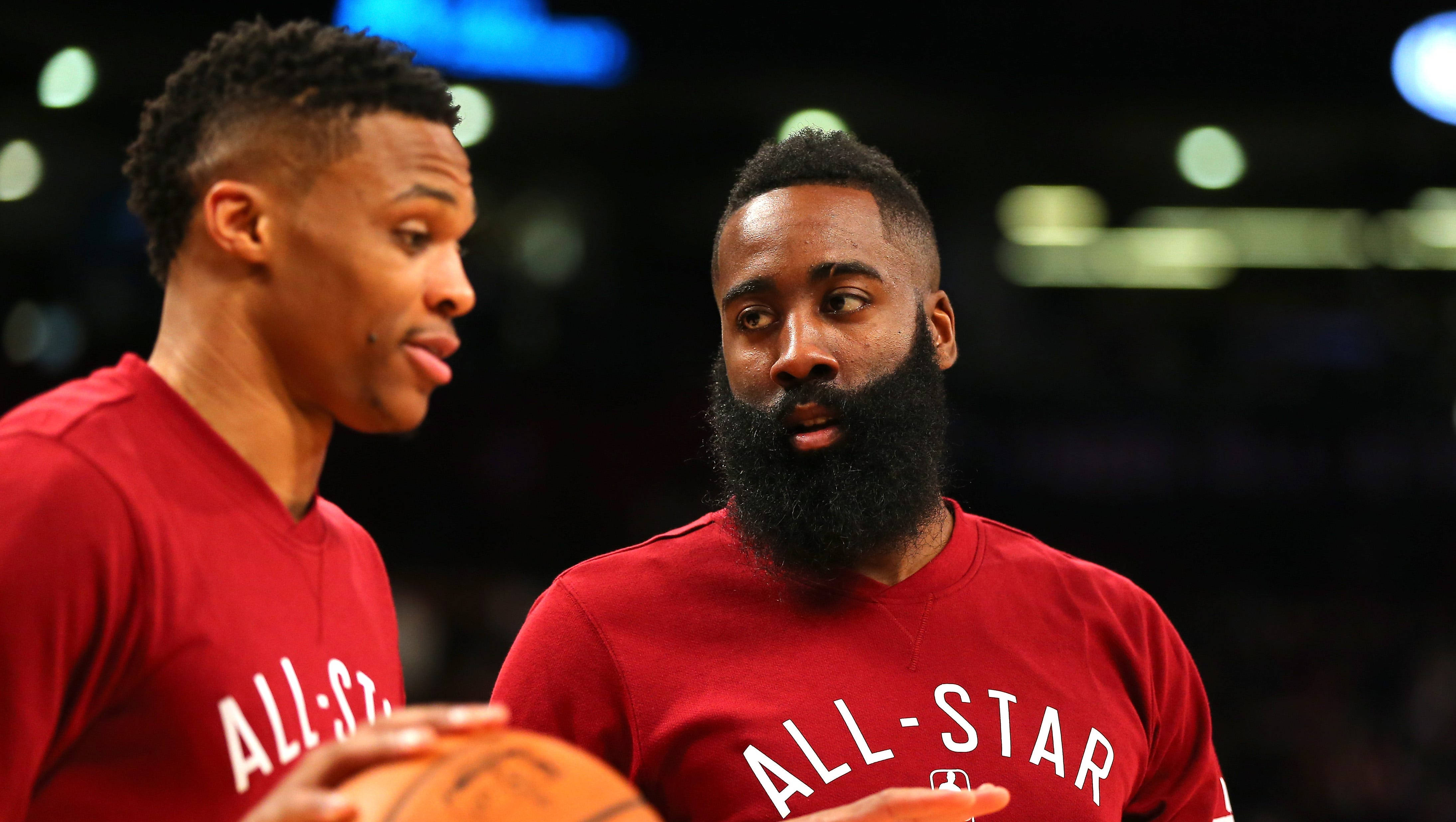James Harden 桌布 壁紙 — 兩名身穿紅色全明星球衣的籃球運動員在場館燈光下激烈交談，同時手持籃球。