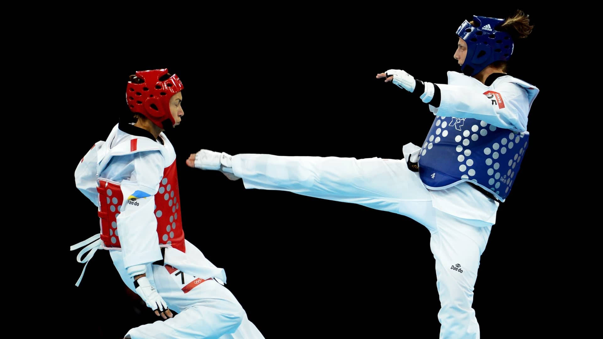 Olympics 桌布 壁紙 — 兩名身穿紅色和藍色裝備的跆拳道運動員在黑色背景下踢腿時碰撞。