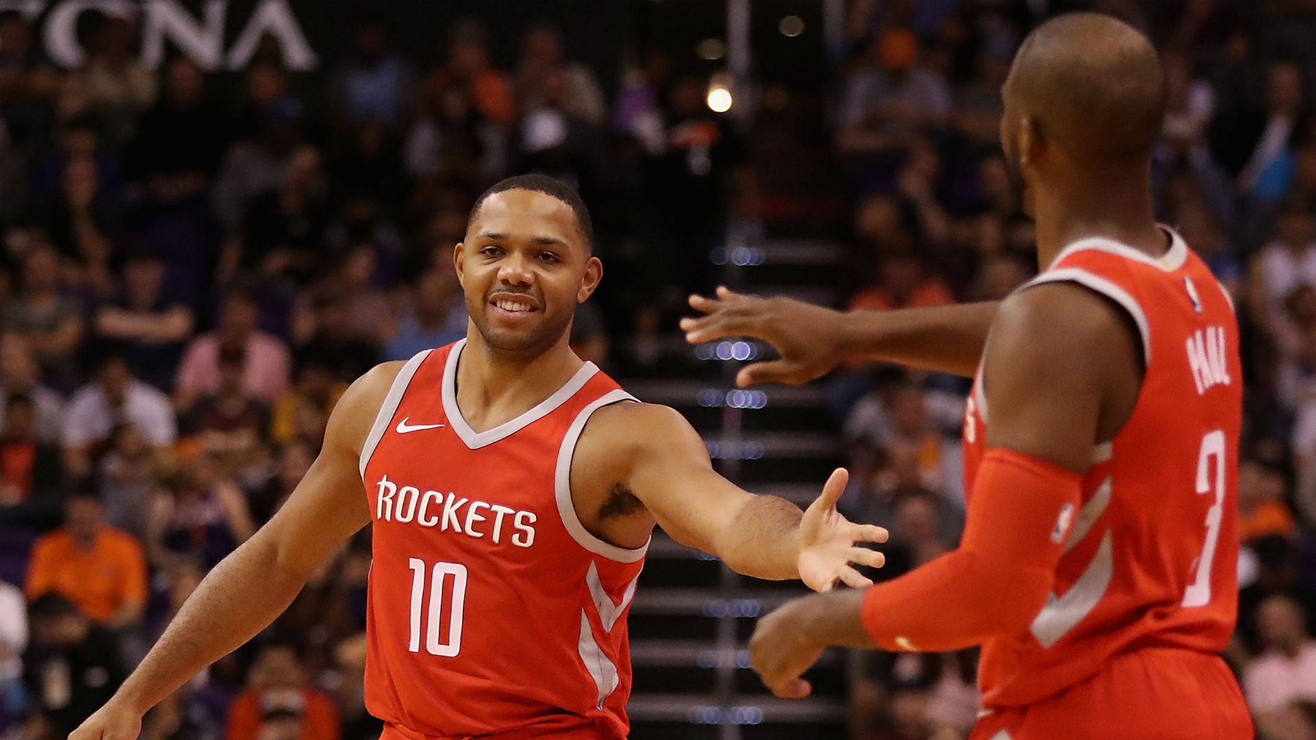 eric gordon 桌布 壁紙 — 兩名身穿紅色球衣的休士頓火箭籃球運動員在比賽中擊掌，身後是模糊的人群。