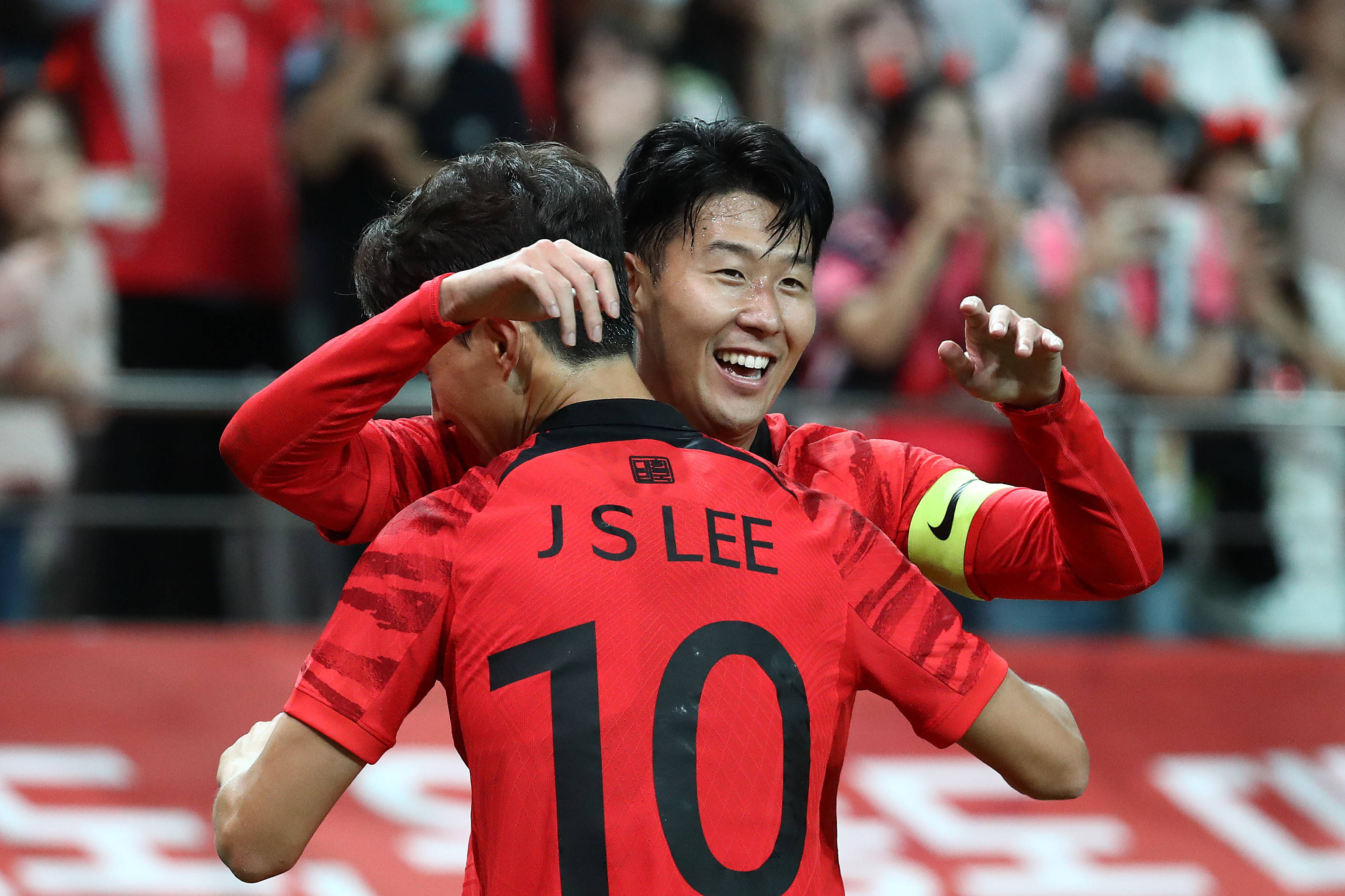 Football Players 桌布 壁紙 — 兩名身穿紅色球衣的快樂足球運動員在體育場上張開雙臂、笑容滿面地慶祝進球。