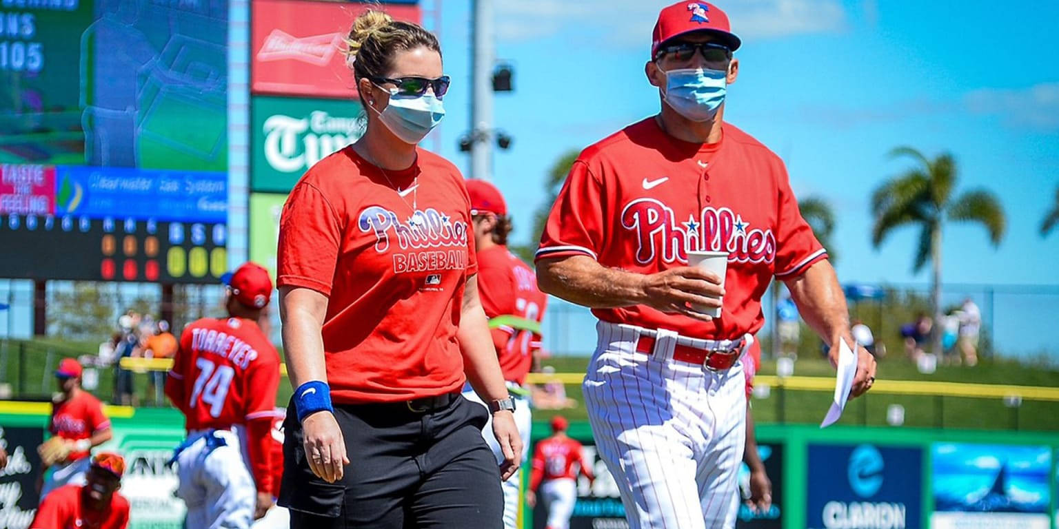 Phillies 桌布 壁紙 — 兩名身穿紅色球衣的費城人棒球運動員在陽光明媚的球場上行走，戴著口罩和太陽眼鏡。