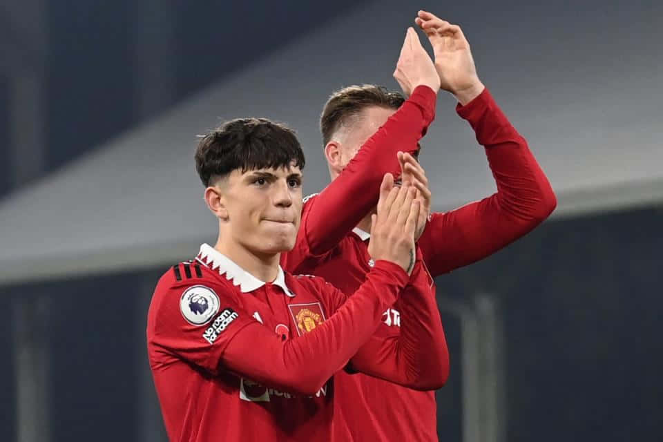 Football Players 桌布 壁紙 — 兩名身穿紅色球衣的足球員在球場燈光下擊掌慶祝。