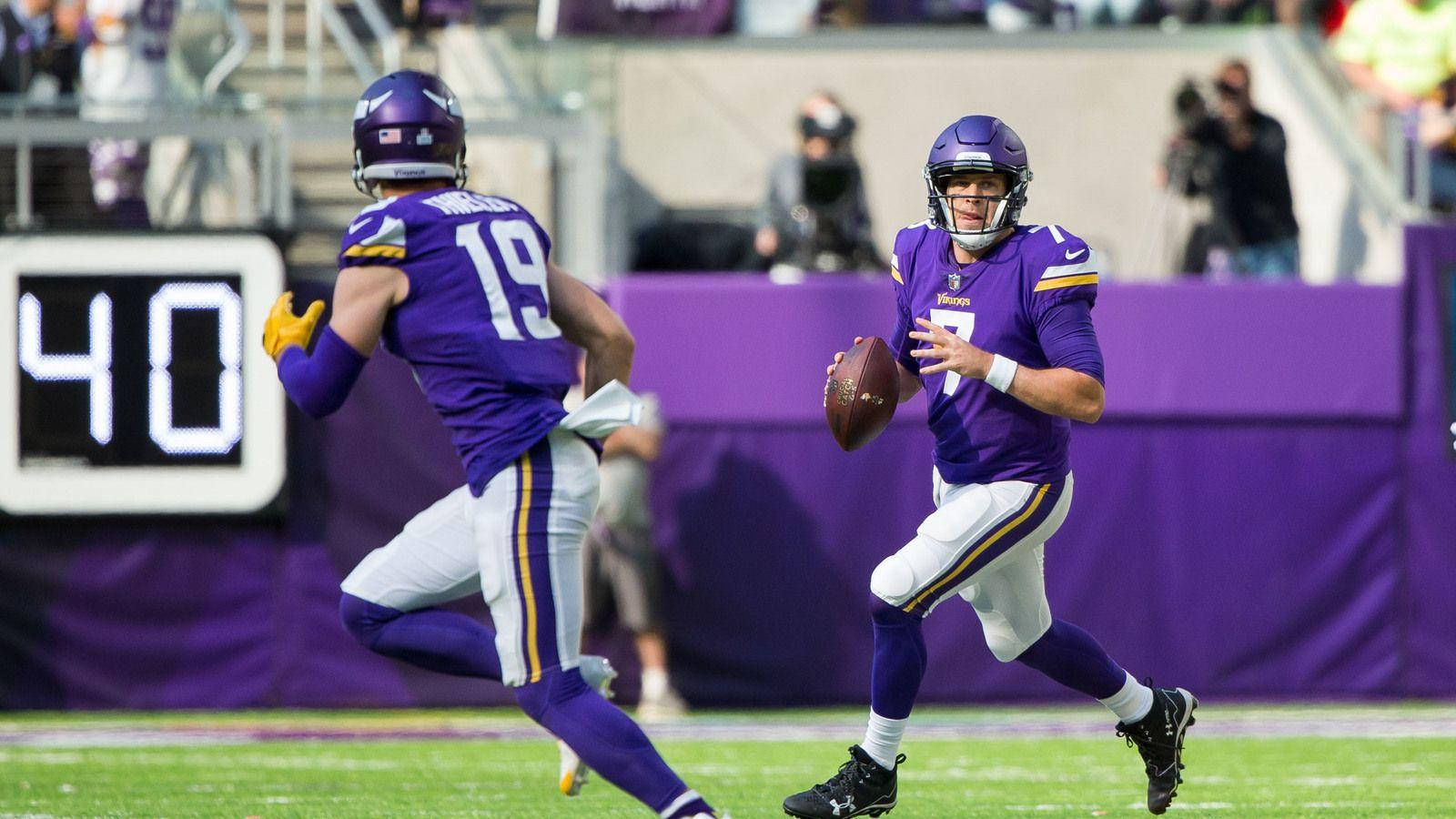 Football Players 桌布 壁紙 — 兩名身穿紫色球衣的明尼蘇達維京人隊美式足球員在陽光明媚的球場上衝刺，比賽中記分板顯示40。