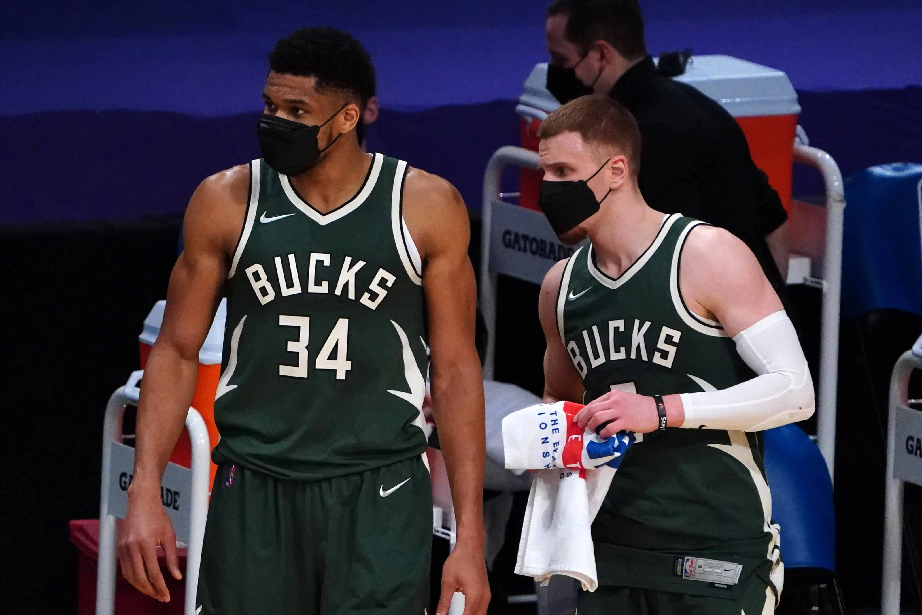 Giannis 桌布 壁紙 — 兩名身穿綠色球衣的密爾瓦基公鹿籃球運動員戴著黑色口罩在球場上行走。