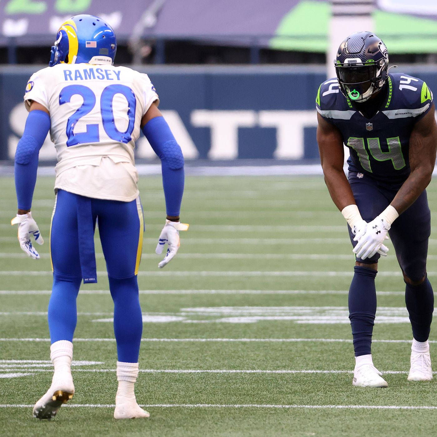 足球 桌布 壁紙 — 兩名身穿藍白球衣的NFL球員在比賽期間站在有白色碼線的綠色球場上。