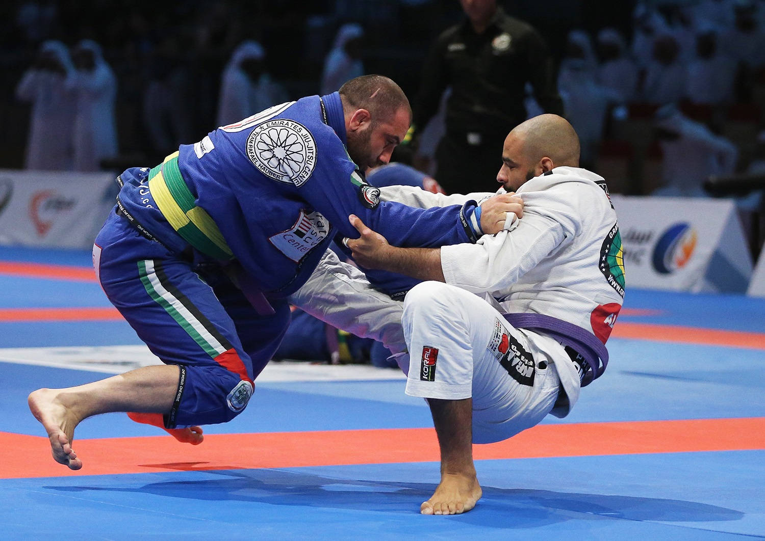 martial arts 桌布 壁紙 — 兩名身穿藍白色柔道服的男柔道運動員在藍紅色墊上進行激烈比賽。