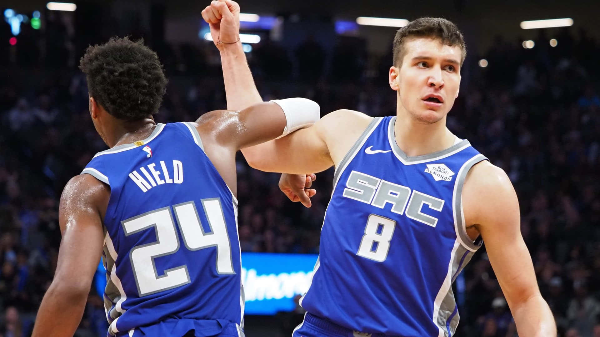 NBA 桌布 壁紙 — 兩名身穿藍色沙加緬度國王隊球衣的籃球運動員在場館燈光下高舉拳頭慶祝一次進攻。