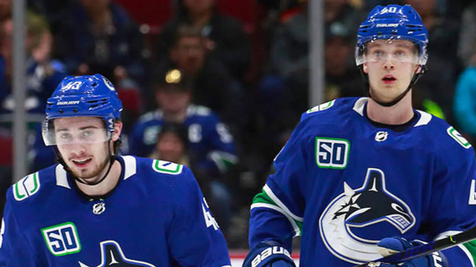 hockey 桌布 壁紙 — 兩名身穿藍色球衣、背號50的溫哥華加人隊（Vancouver Canucks）冰球球員在比賽中站在冰上，背景有觀眾。