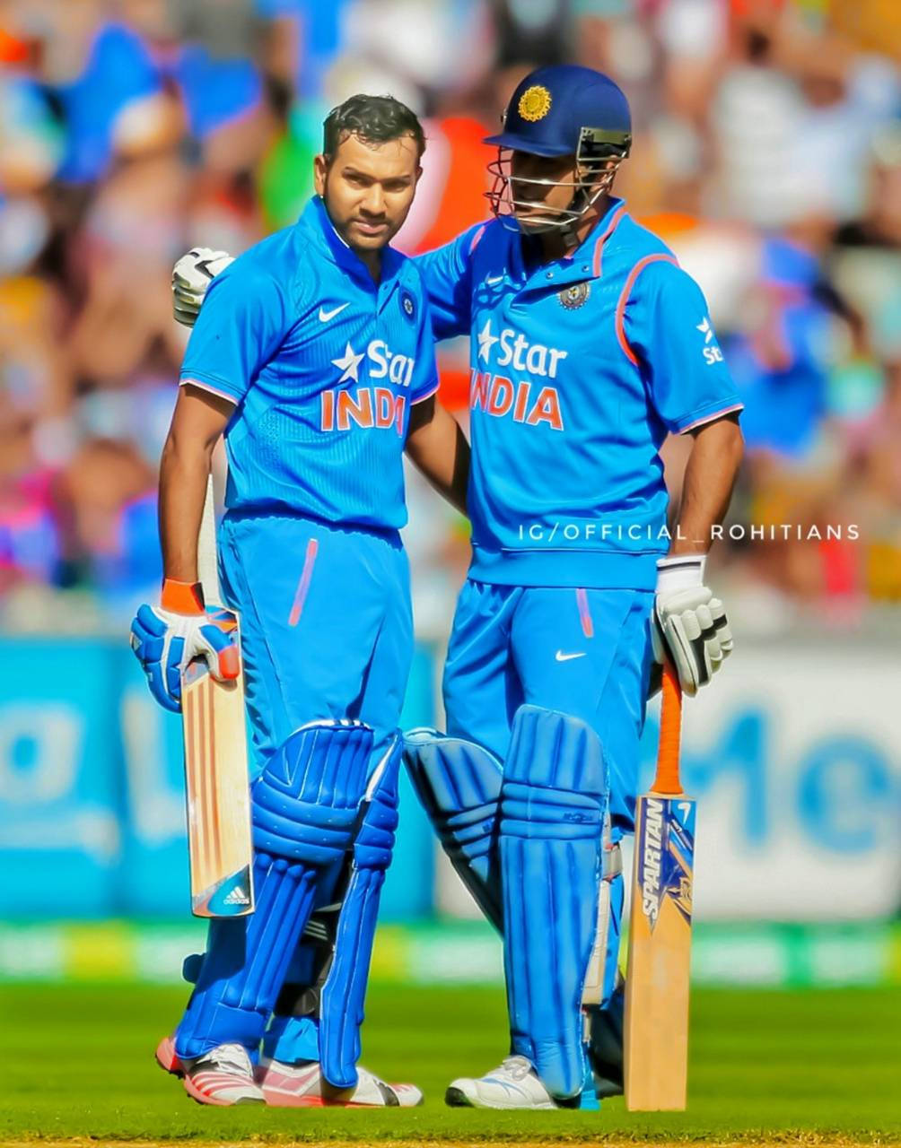 Rohit Sharma 桌布 壁紙 — 兩名身穿藍色球衣的印度板球運動員站在陽光明媚的綠色球場上，其中一人將支持的手臂搭在另一人的肩膀上。