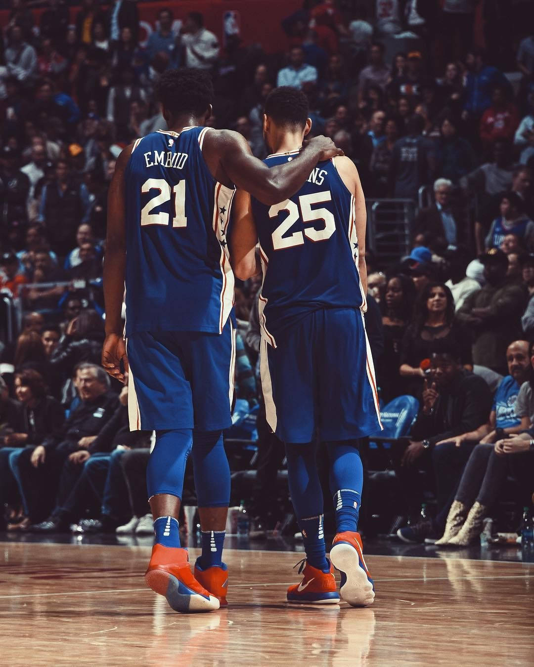 NBA 桌布 壁紙 — 兩名身穿藍色球衣的籃球運動員在場館燈光下的拋光球場上互相搭著肩膀。