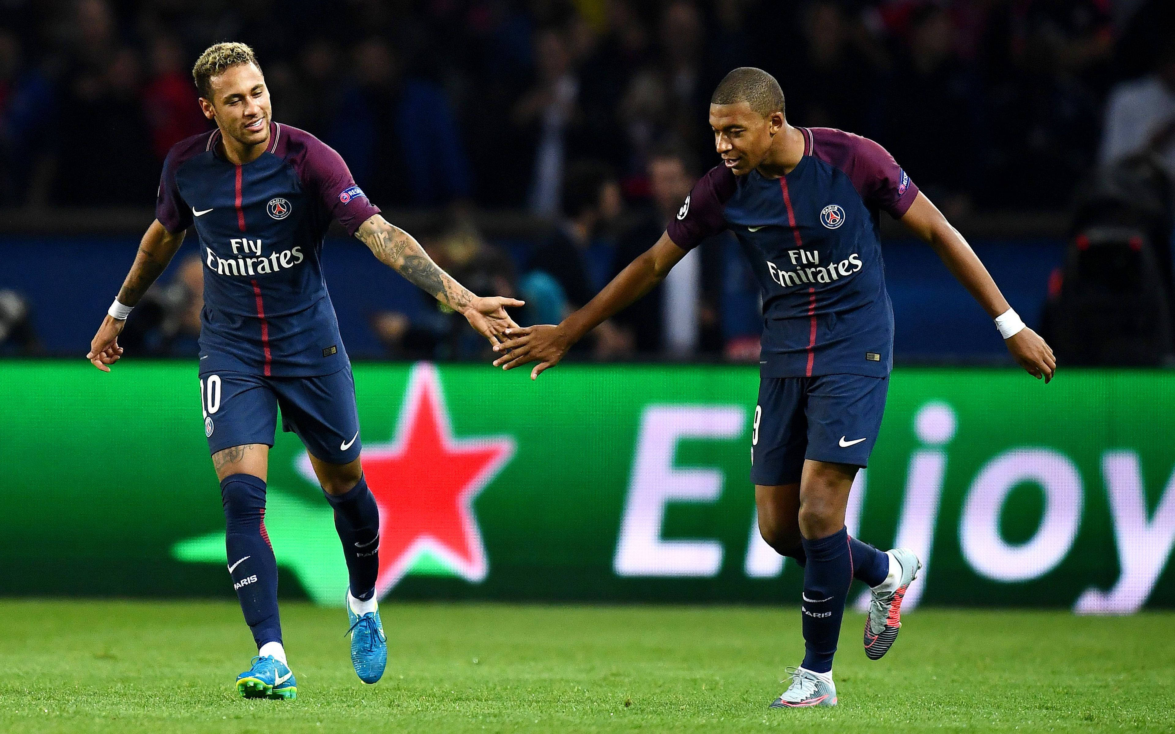Champions League 桌布 壁紙 — 兩名身穿藍色球衣的足球員在夜間燈光下的照明球場上擊掌。