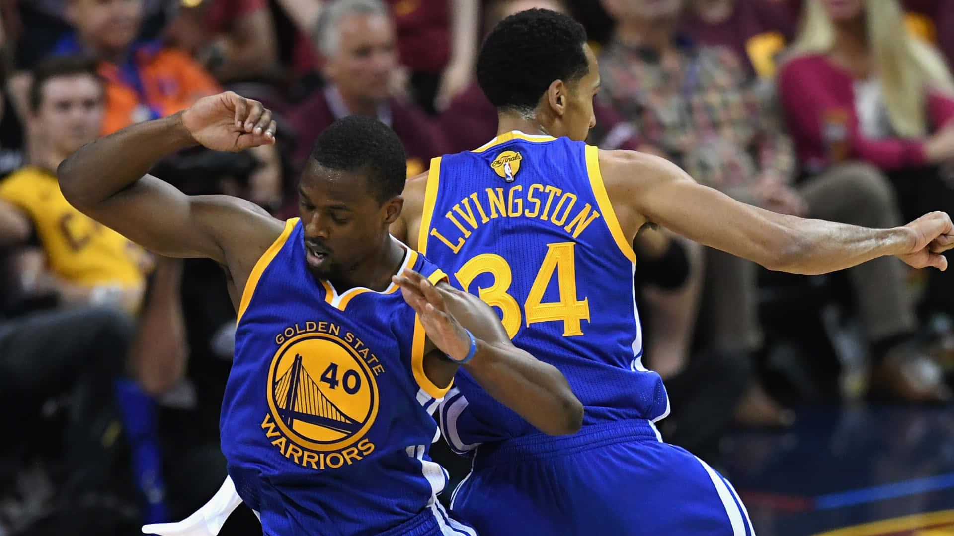 NBA 桌布 壁紙 — 兩名身穿藍色球衣的金州勇士籃球運動員在比賽中激烈慶祝，背景為模糊的人群。