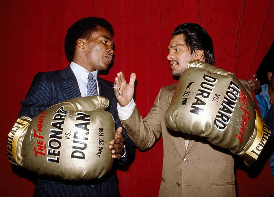 紅色動圖 桌布 壁紙 — 兩名身穿西裝的拳擊手面對面，手持印有「Leonard vs Duran 1980年6月20日」字樣的巨型拳擊手套，背景是紅色帷幕。