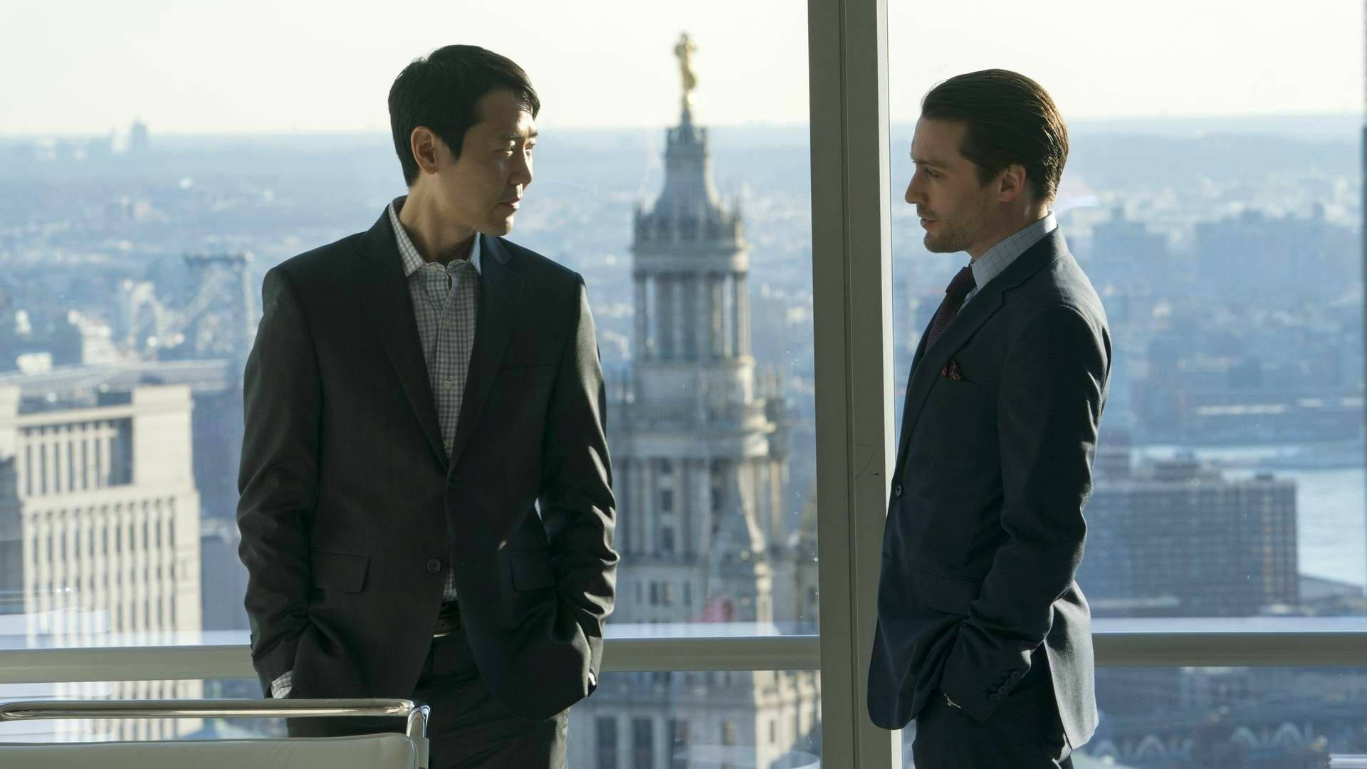 Succession 桌布 壁紙 — 兩名身穿西裝的男子在一間可欣賞全景城市景觀的高層辦公室中面對面站立。