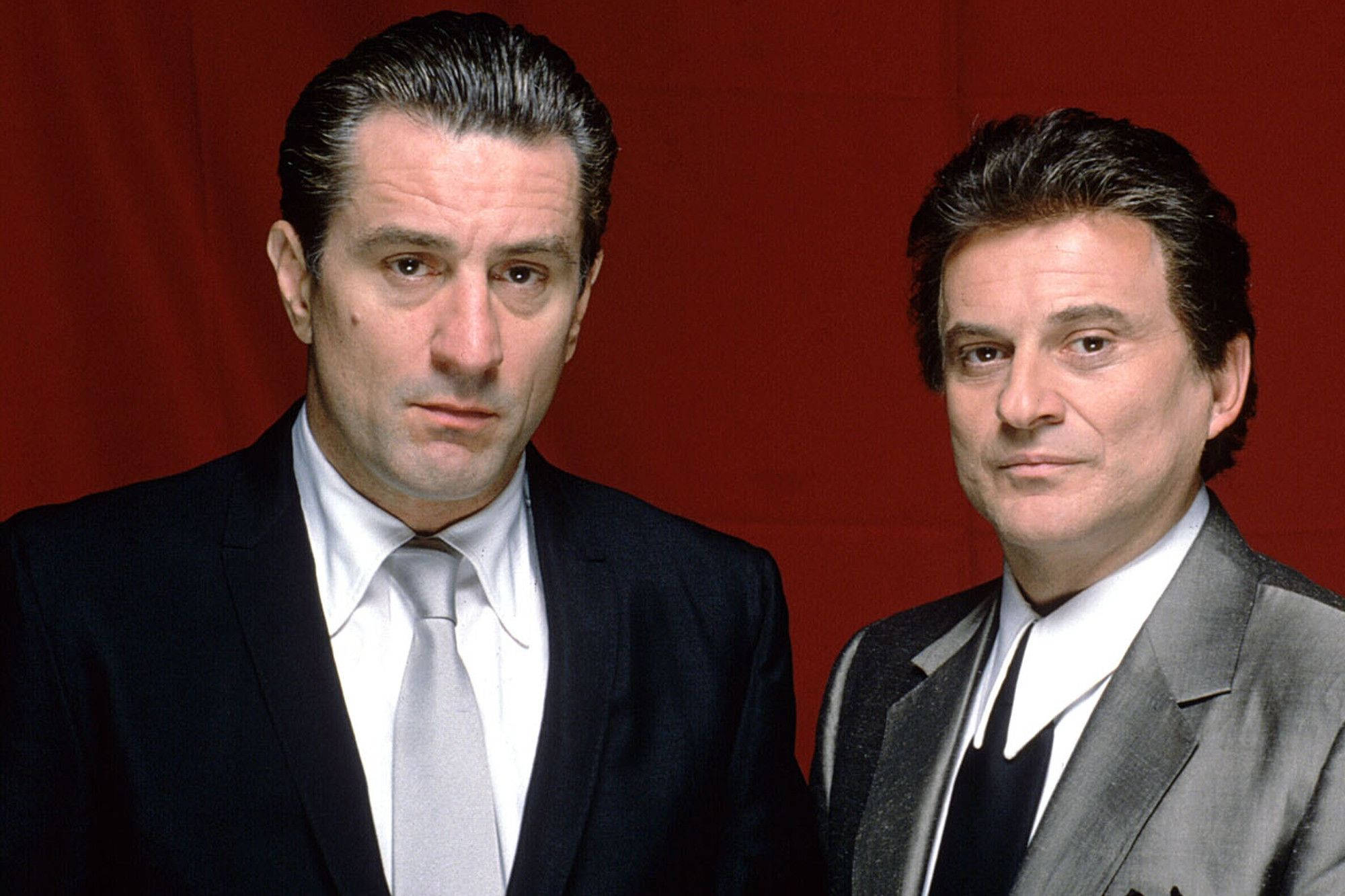 Robert De Niro 桌布 壁紙 — 兩名身穿西裝的男子站在深紅色背景前，表情嚴肅，頭髮經過造型。