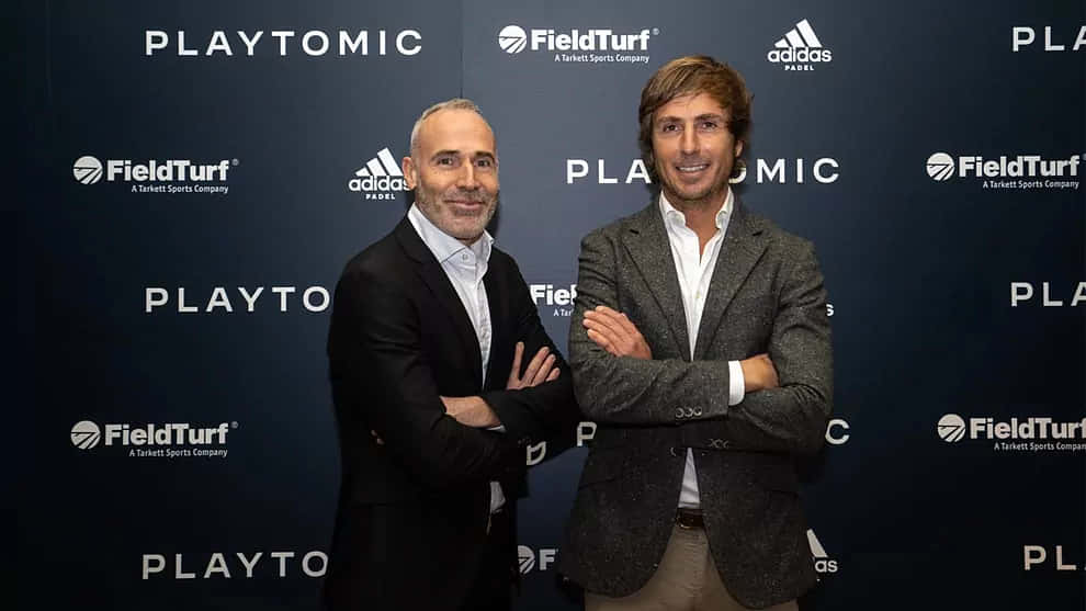 Celebrity 桌布 壁紙 — 兩名身穿西裝的男子自信地交叉雙臂，站在帶有Playtomic FieldTurf和adidas標誌的深藍色品牌背景前。