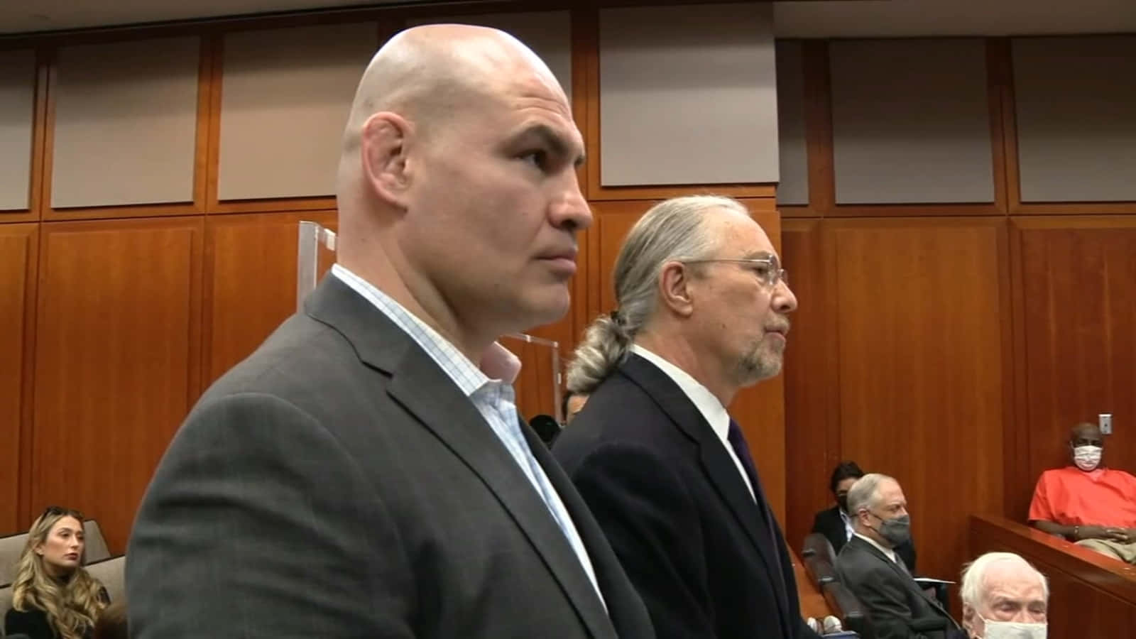 UFC 桌布 壁紙 — 兩名身穿西裝的男子莊嚴地站在木質鑲板的法庭內，背景有其他人坐著。
