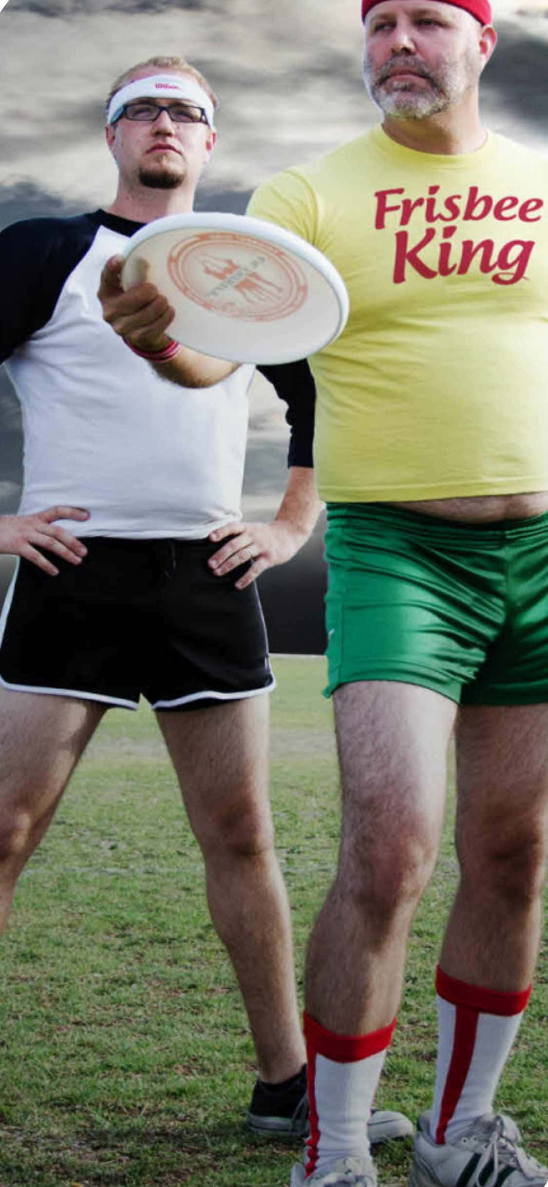 運動 桌布 壁紙 — 兩名身穿運動裝備的男子在戶外擺姿勢，一人手持飛盤，另一人穿著黃色「Frisbee King」T恤。