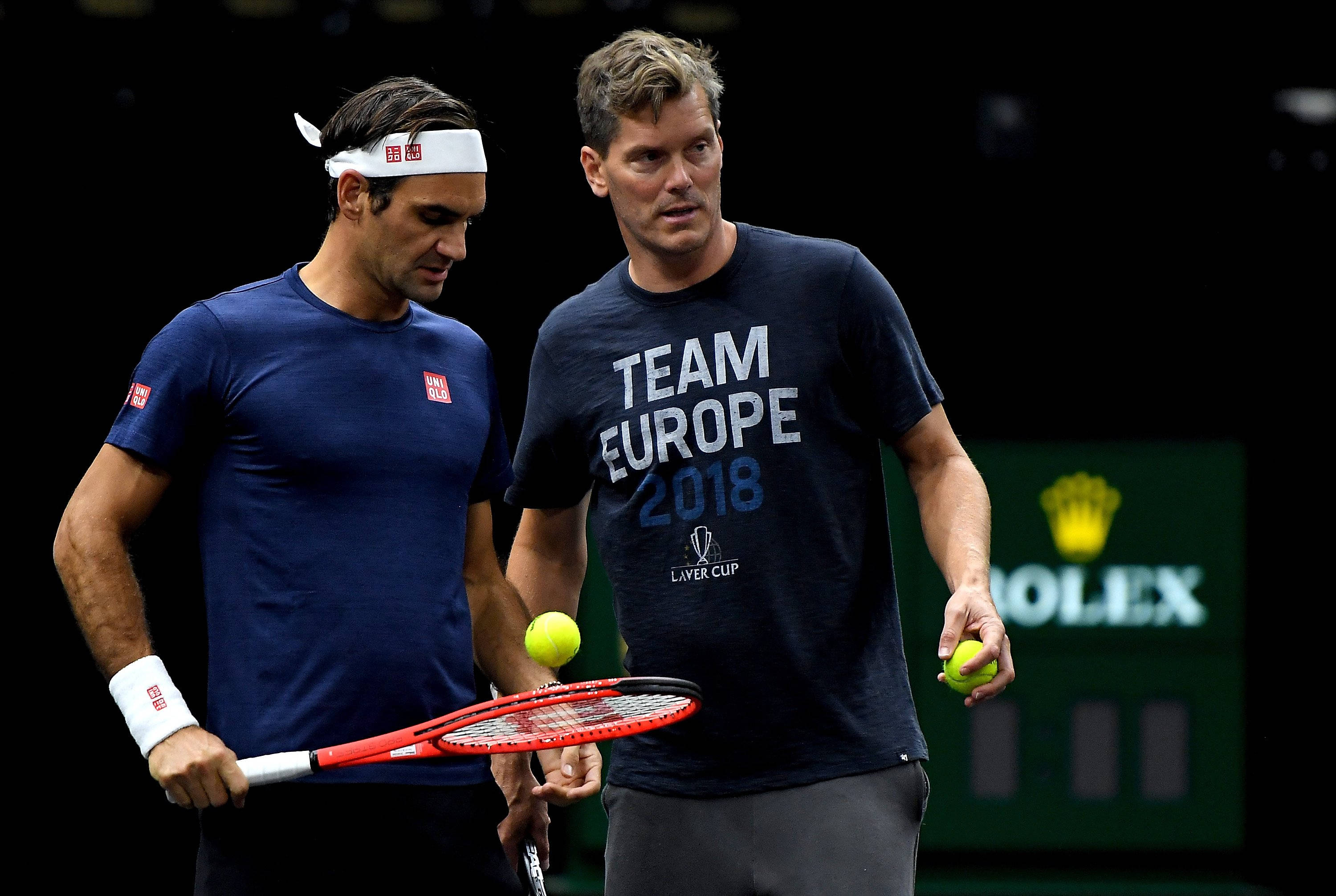 Tennis 桌布 壁紙 — 兩名身穿隊服的男子網球選手在比賽期間站在球場上，手持球拍和網球。
