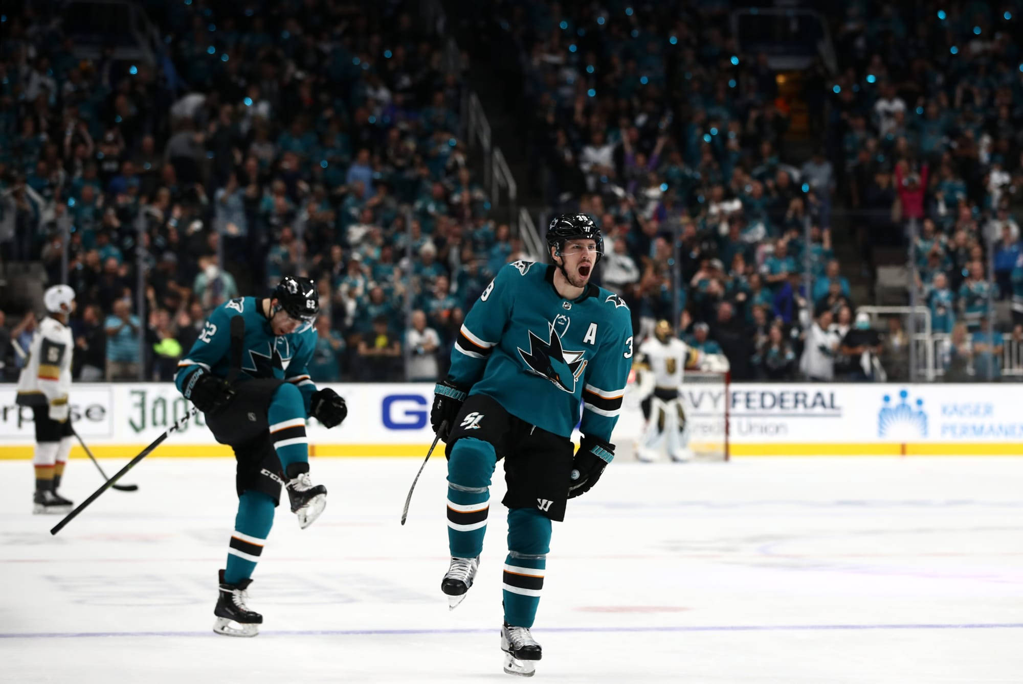 hockey 桌布 壁紙 — 兩名身穿青綠色球衣的曲棍球運動員在冰上慶祝進球，身後有群眾歡呼。
