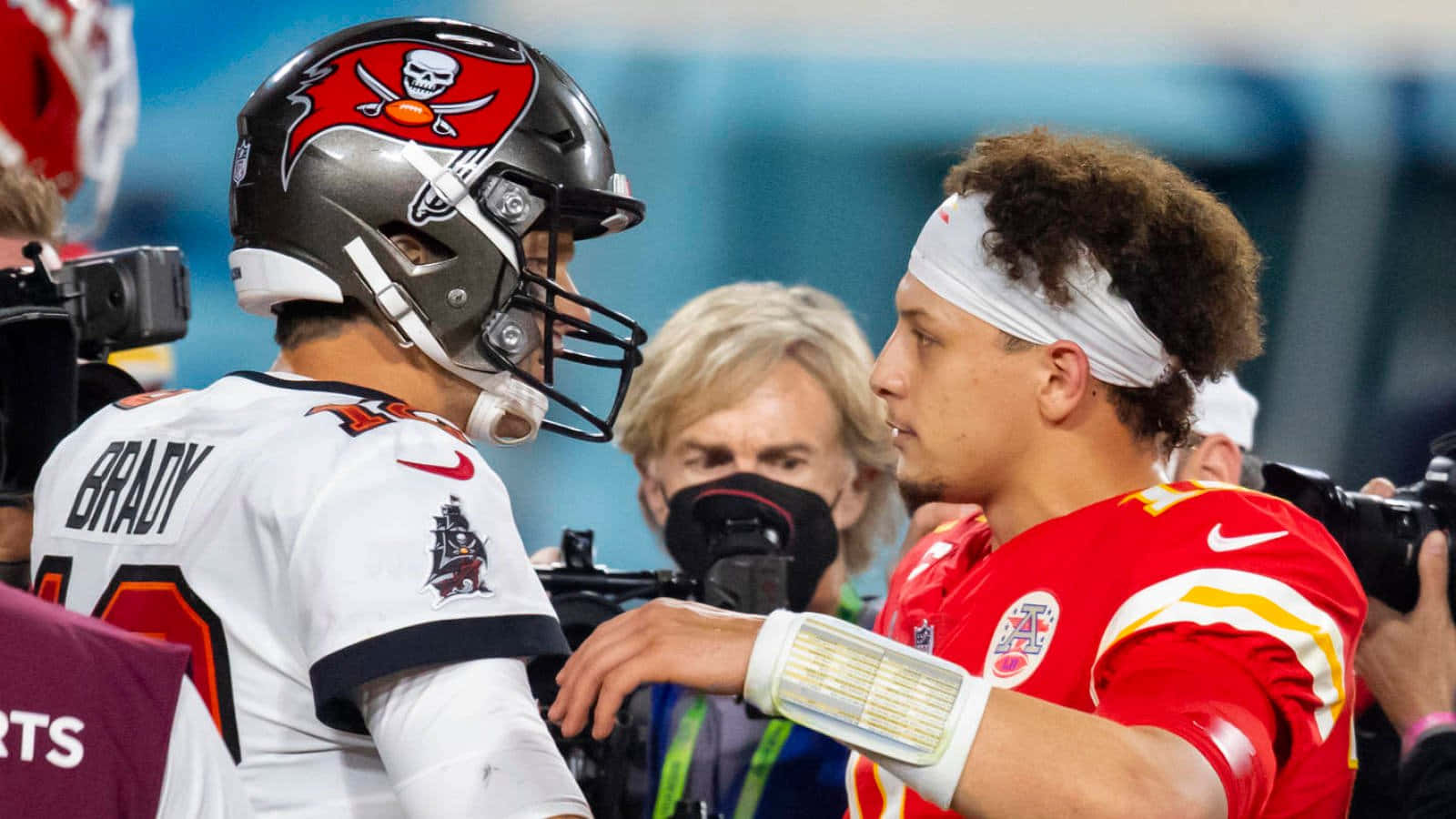 Madden NFL 22 桌布 壁紙 — 兩名身穿頭盔和球衣的NFL四分衛在比賽中對峙，周圍有攝影機和記者。