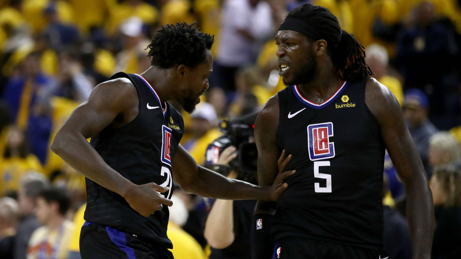 montrezl harrell 桌布 壁紙 — 兩名身穿黑色LA快艇隊球衣的籃球運動員在比賽中激烈交流，背景是黃色的人群。