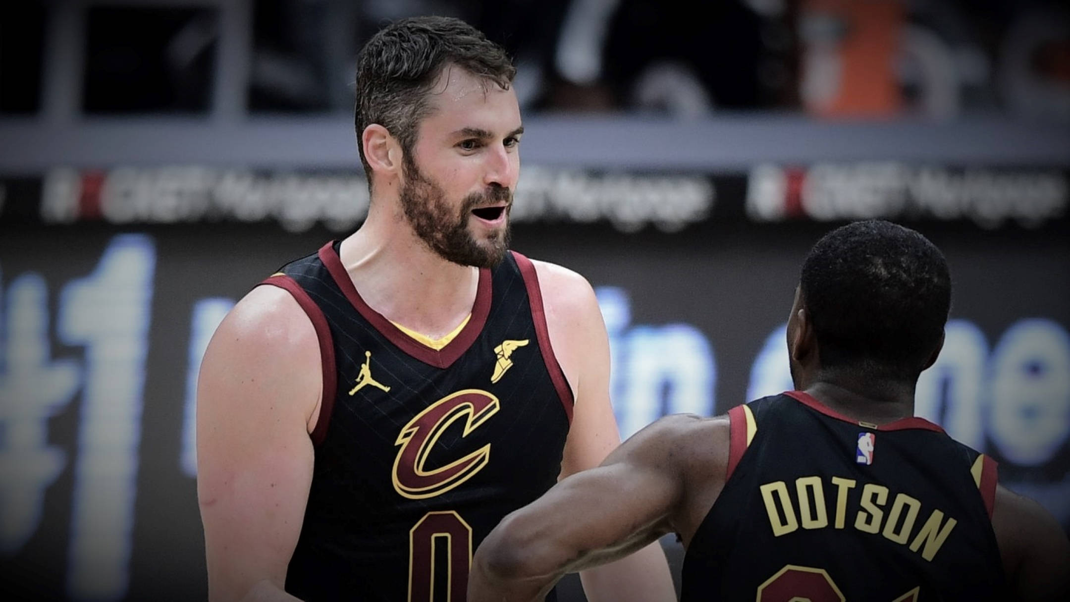 Kevin Love 桌布 壁紙 — 兩名身穿黑色克里夫蘭騎士隊球衣的籃球運動員在明亮的場館燈光下，在比賽中進行專注的交談。