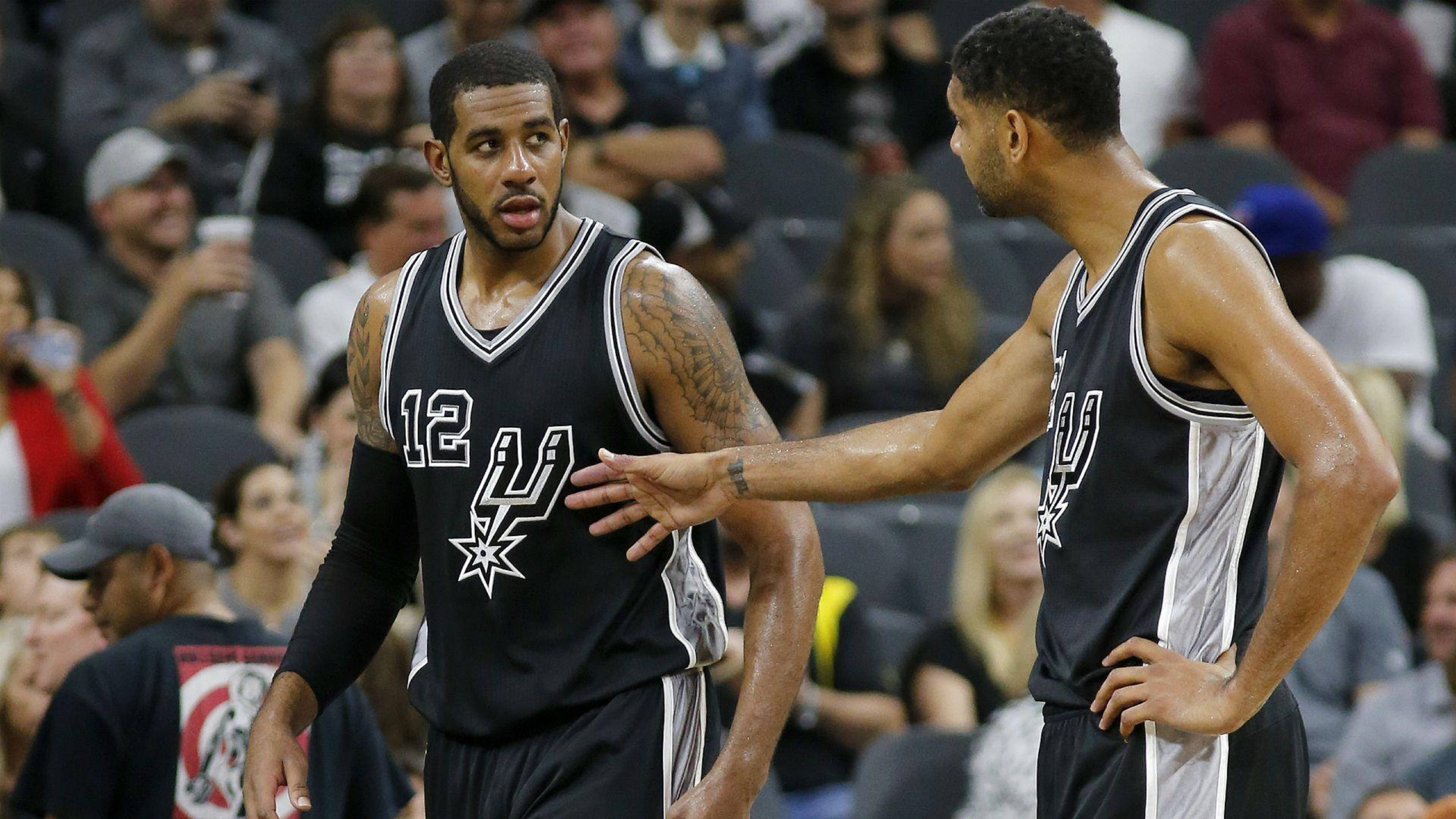 Lamarcus Aldridge 桌布 壁紙 — 兩名身穿黑色和銀色球衣的聖安東尼奧馬刺籃球運動員在比賽中專注交談，背景是模糊的人群。