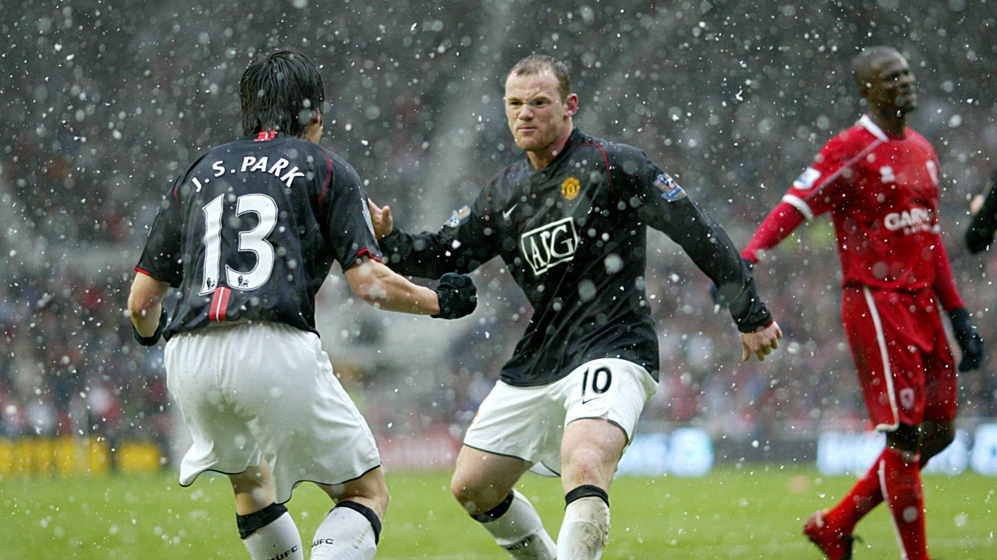 Rooney 桌布 壁紙 — 兩名身穿黑色球衣的足球運動員在雪中慶祝進球，濕滑的球場上附近有一名身穿紅色的對手。