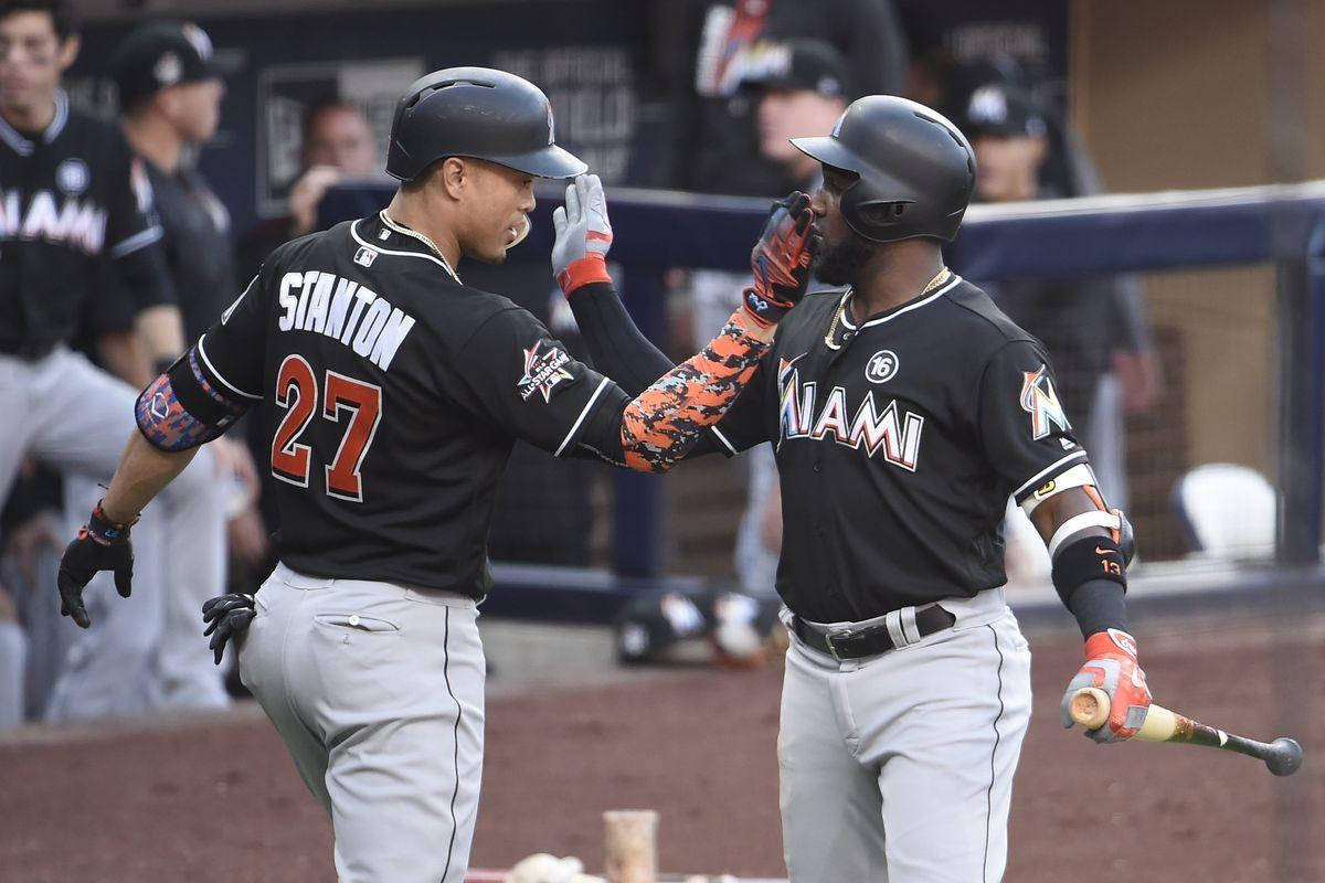 MLB 桌布 壁紙 — 兩名身穿黑色球衣的邁阿密棒球運動員在比賽期間於泥地球場上擊掌。