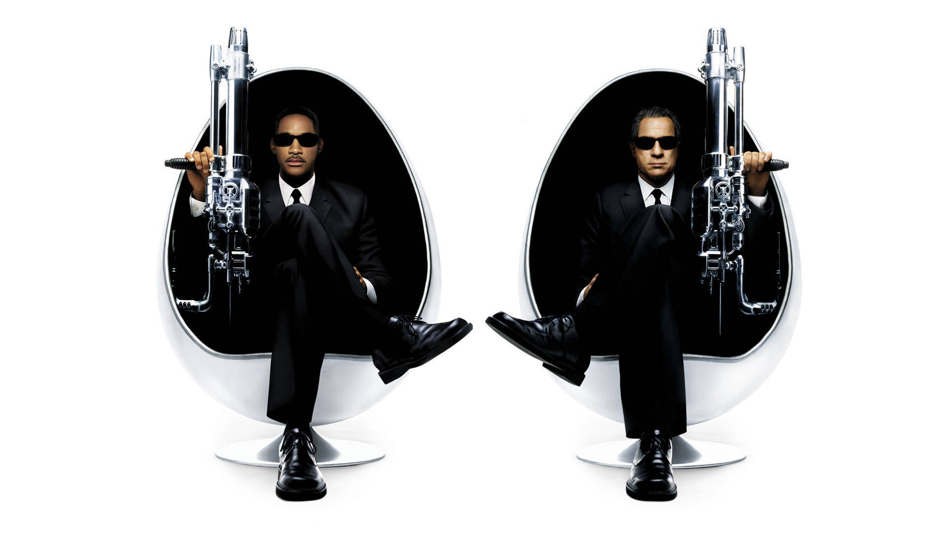 Men In Black 桌布 壁紙 — 兩名身穿黑色西裝、戴著太陽眼鏡的男子坐在白色蛋形椅上，手持銀色手槍，背景是純白色。