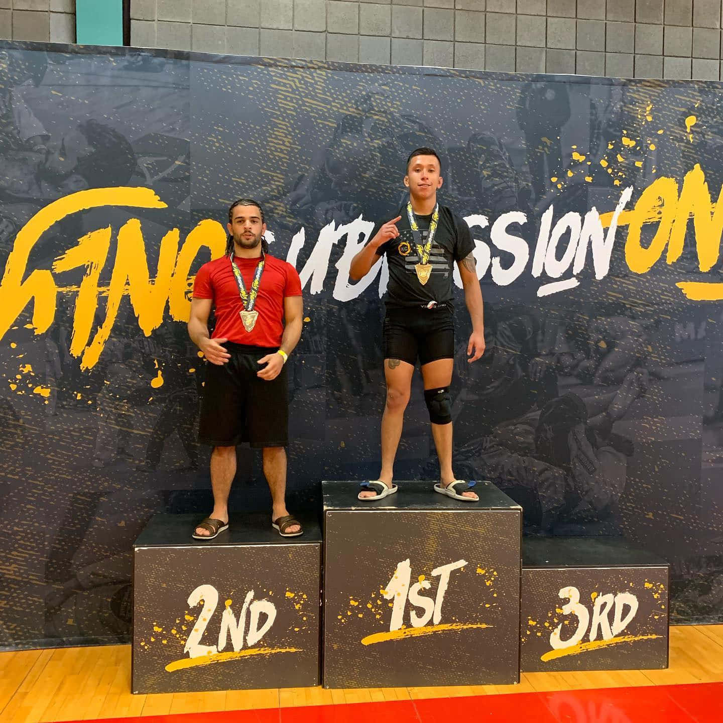 MMA 桌布 壁紙 — 兩名運動員站在比賽頒獎台上，一個第一名，另一個第二名，兩人都戴著獎牌和穿著運動裝備。