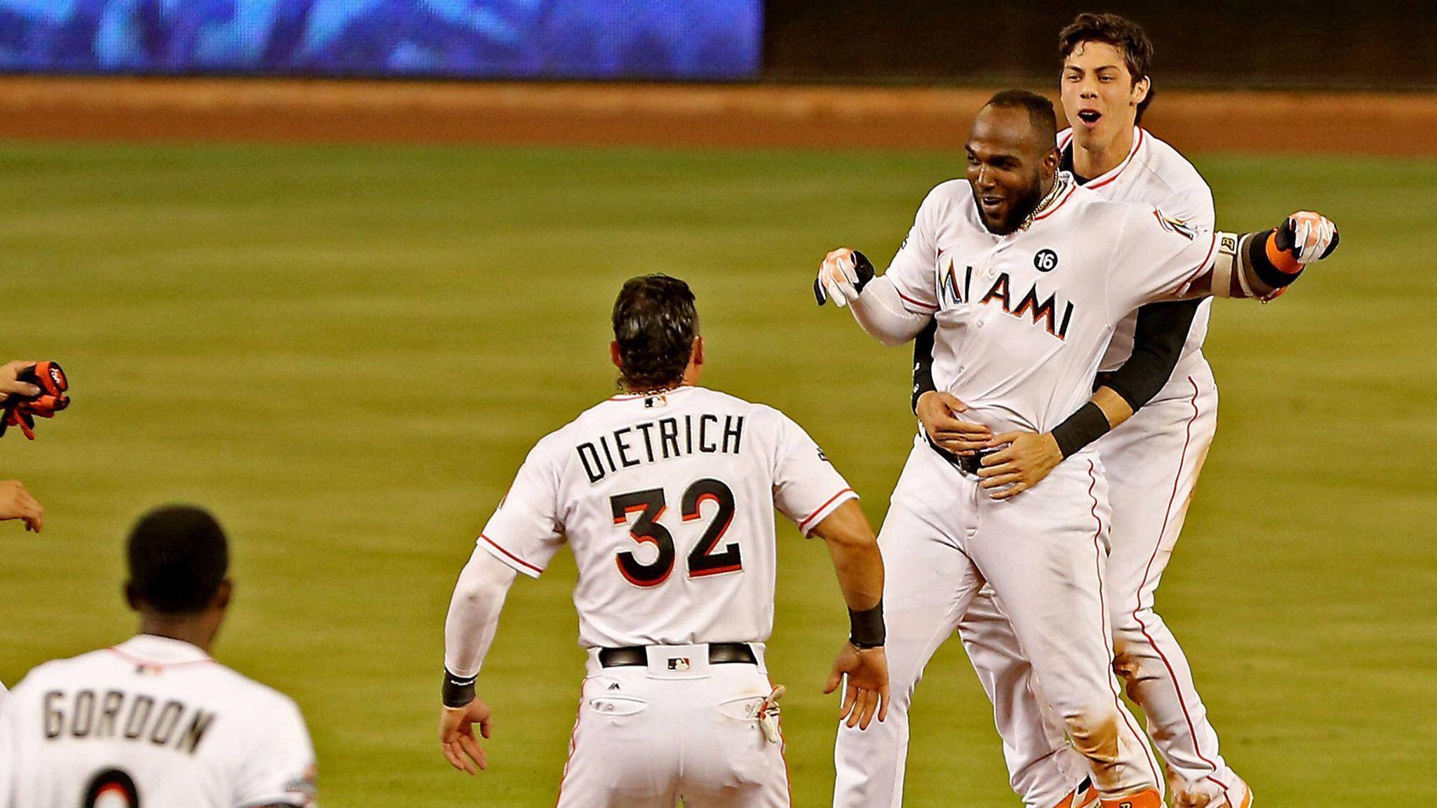 MLB 桌布 壁紙 — 兩名邁阿密棒球運動員在夜間光線充足的場地上以高能量慶祝一次比賽。