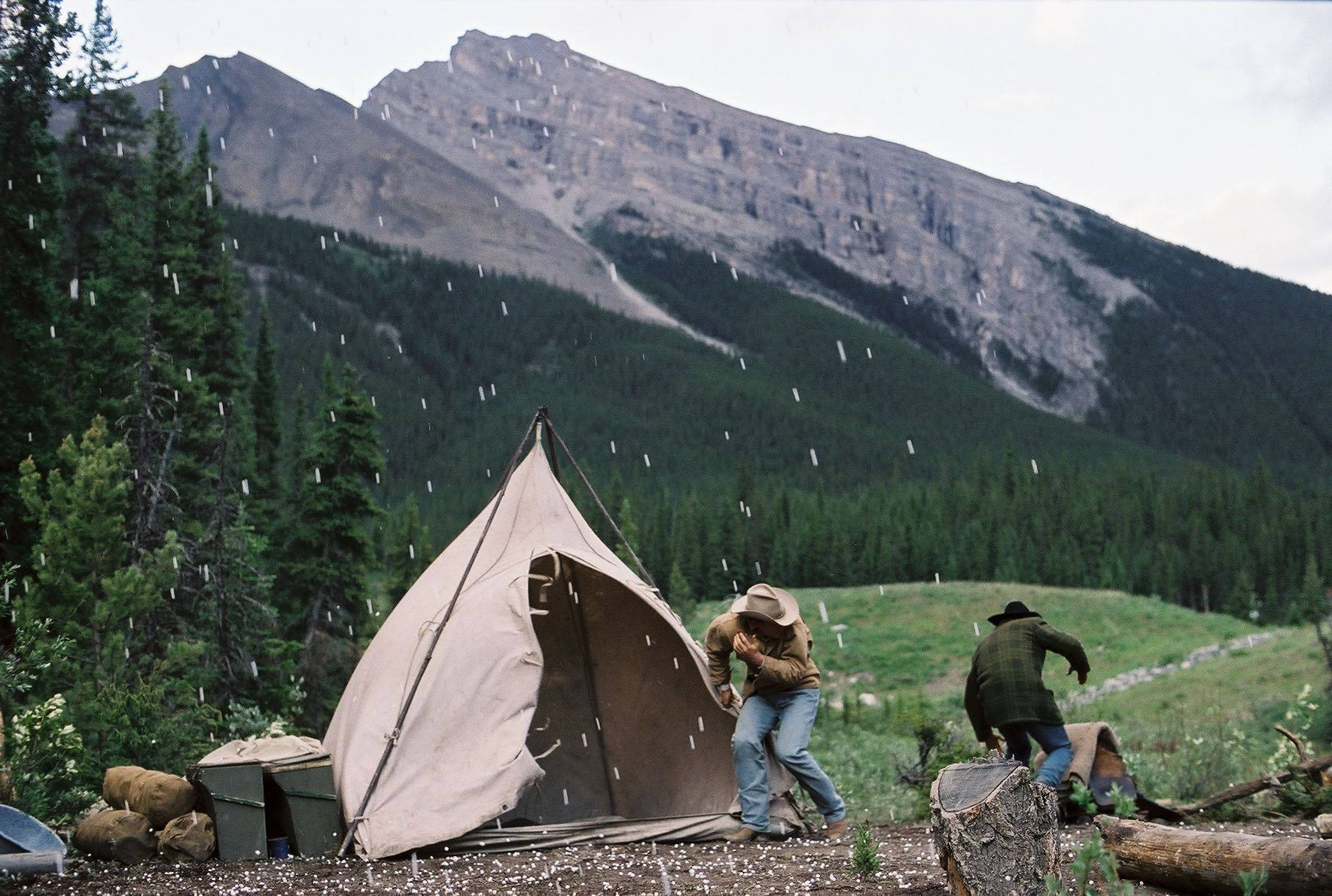 brokeback mountain 桌布 壁紙 — 兩名露營者在下雨的森林山谷中匆忙搭建一個棕色帳篷。