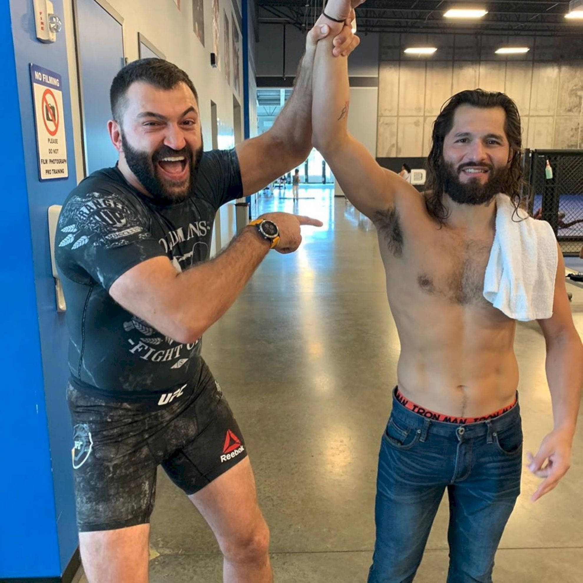 UFC 桌布 壁紙 — 兩名鬍鬚男在健身房訓練後舉起手臂，面露喜悅慶祝勝利。