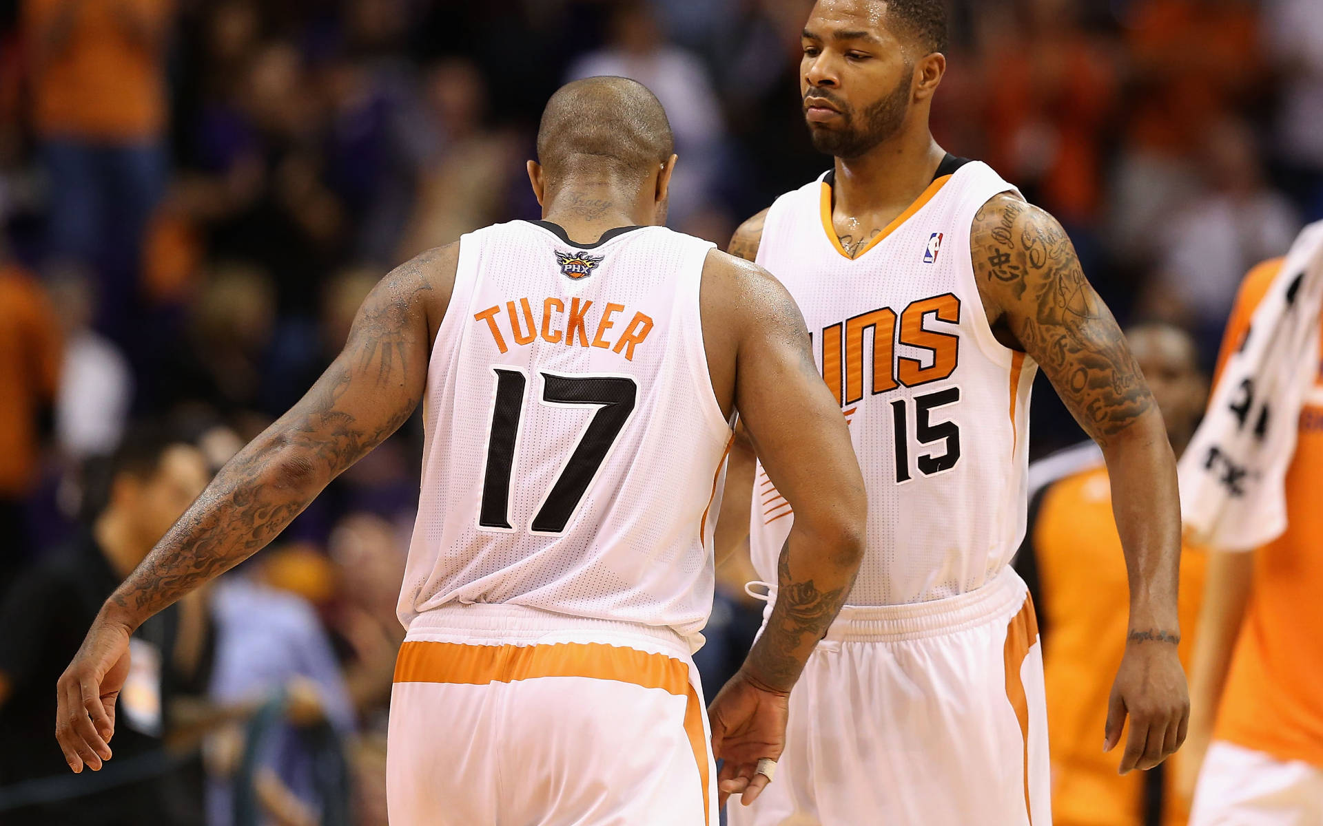 Suns 桌布 壁紙 — 兩名鳳凰城太陽隊籃球運動員身穿白色和橙色球衣在比賽中緊密站立，手臂上的紋身清晰可見。