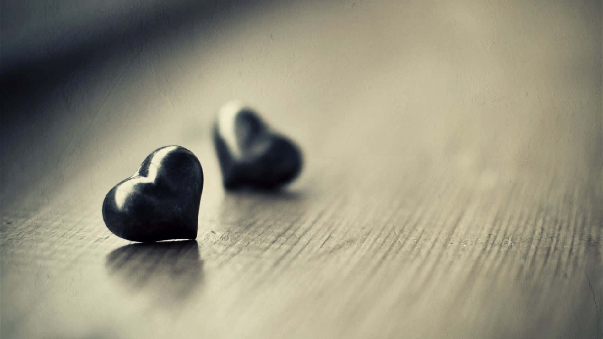 Lovers 桌布 壁紙 — 兩塊光滑的黑色心形石頭放置在紋理木質表面上，景深較淺。