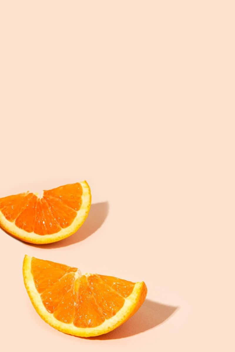 Cute Orange 桌布 壁紙 — 兩塊多汁的柳橙片放在柔軟的蜜桃色背景上，投下微妙的陰影。