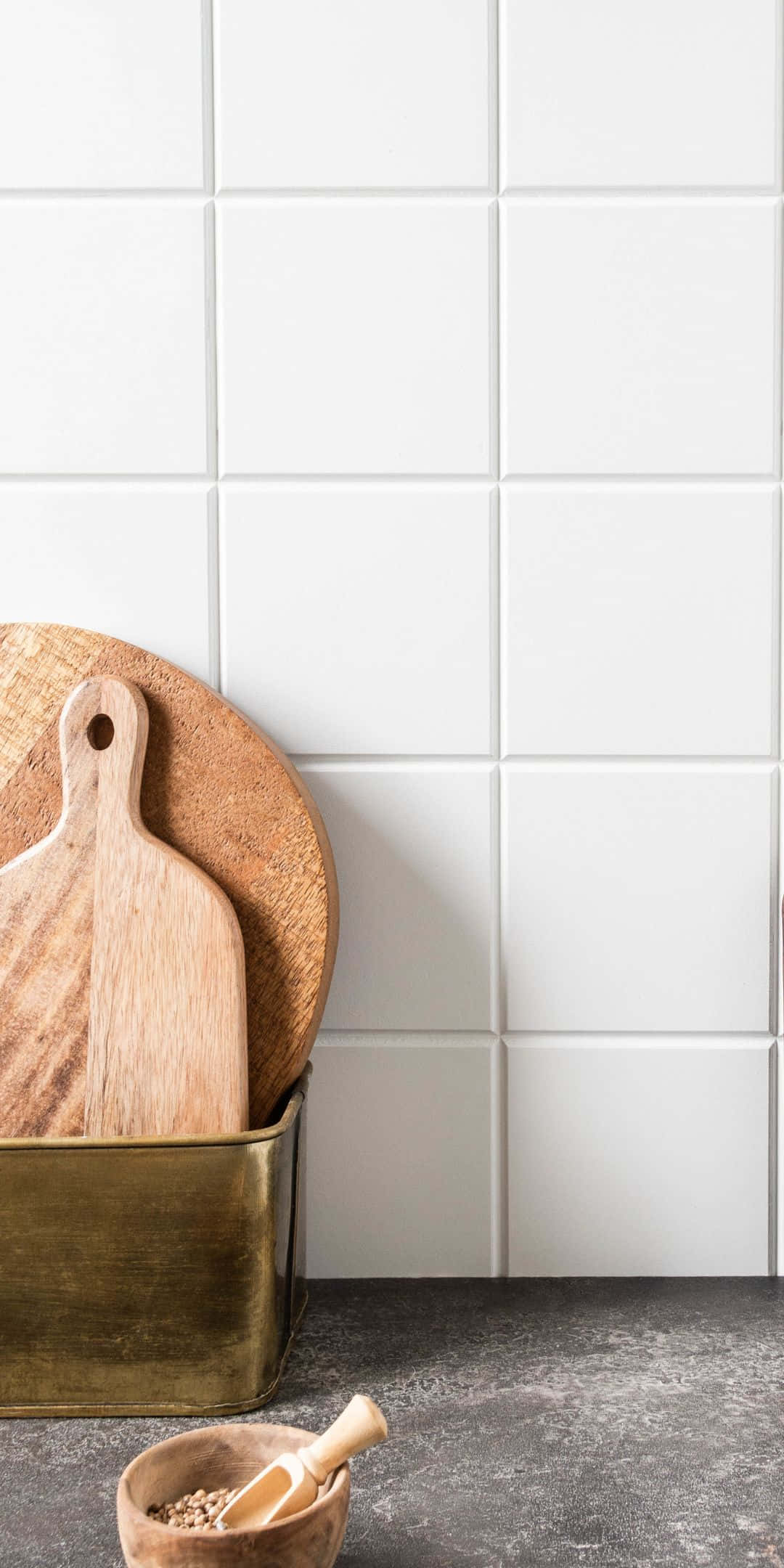 Pixel 3 Kitchen 桌布 壁紙 — 兩塊木製砧板放在一個黃銅容器中，靠著白色瓷磚廚房牆壁，附近有一個小木碗。