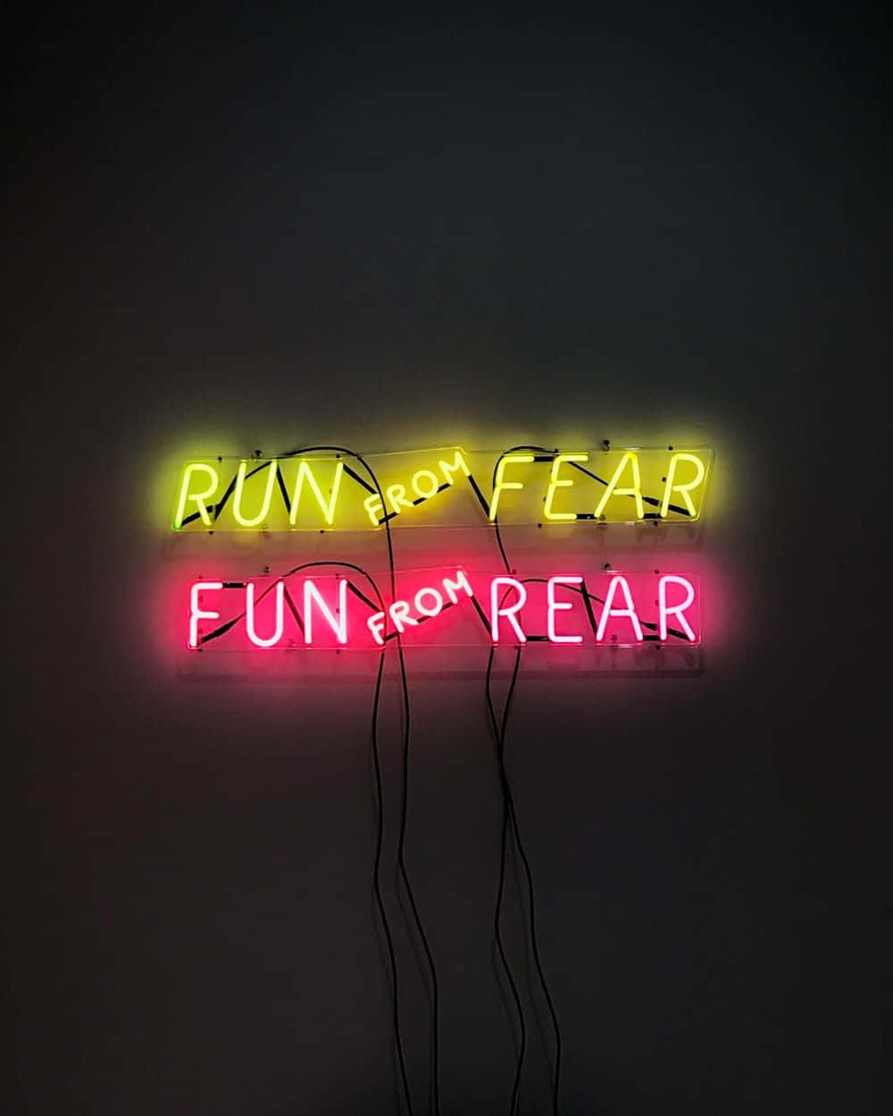 Inspirational Phone 桌布 壁紙 — 兩塊發光的霓虹燈牌在暗牆上，一塊黃色寫著 run from fear，一塊粉紅色寫著 fun from rear。