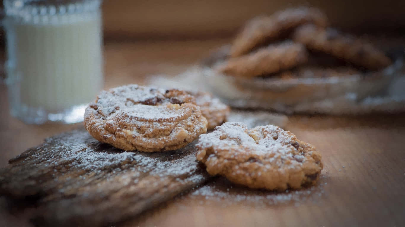 1366x768 Cookies 桌布 壁紙 — 兩塊糖粉餅乾放在一塊鄉村風木板上，旁邊有一杯牛奶，背景還有更多模糊的餅乾。