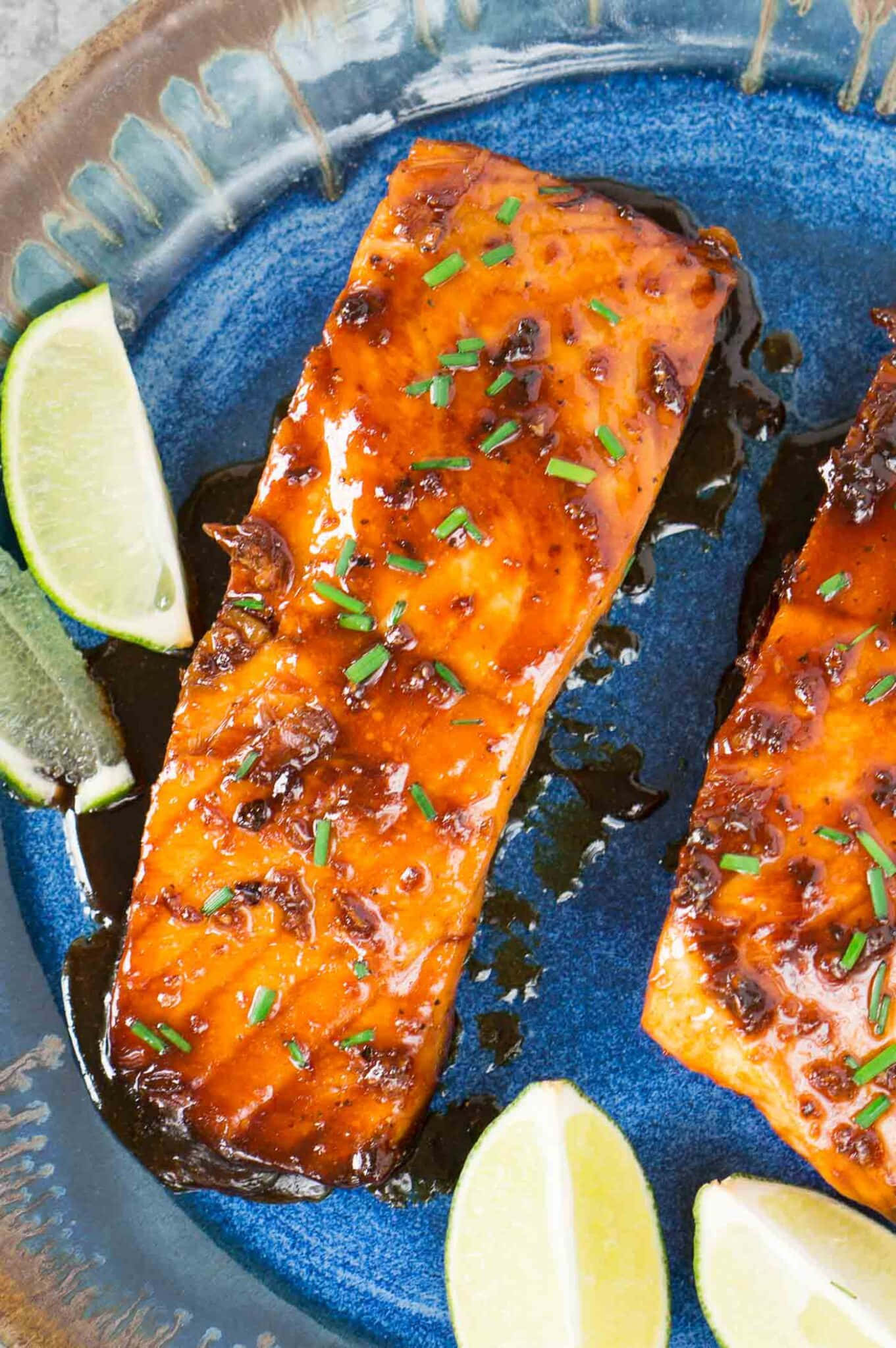 Salmon 桌布 壁紙 — 兩塊釉面鮭魚菲力，飾以細香蔥和萊姆角，放在有紋理的藍色陶瓷盤上。