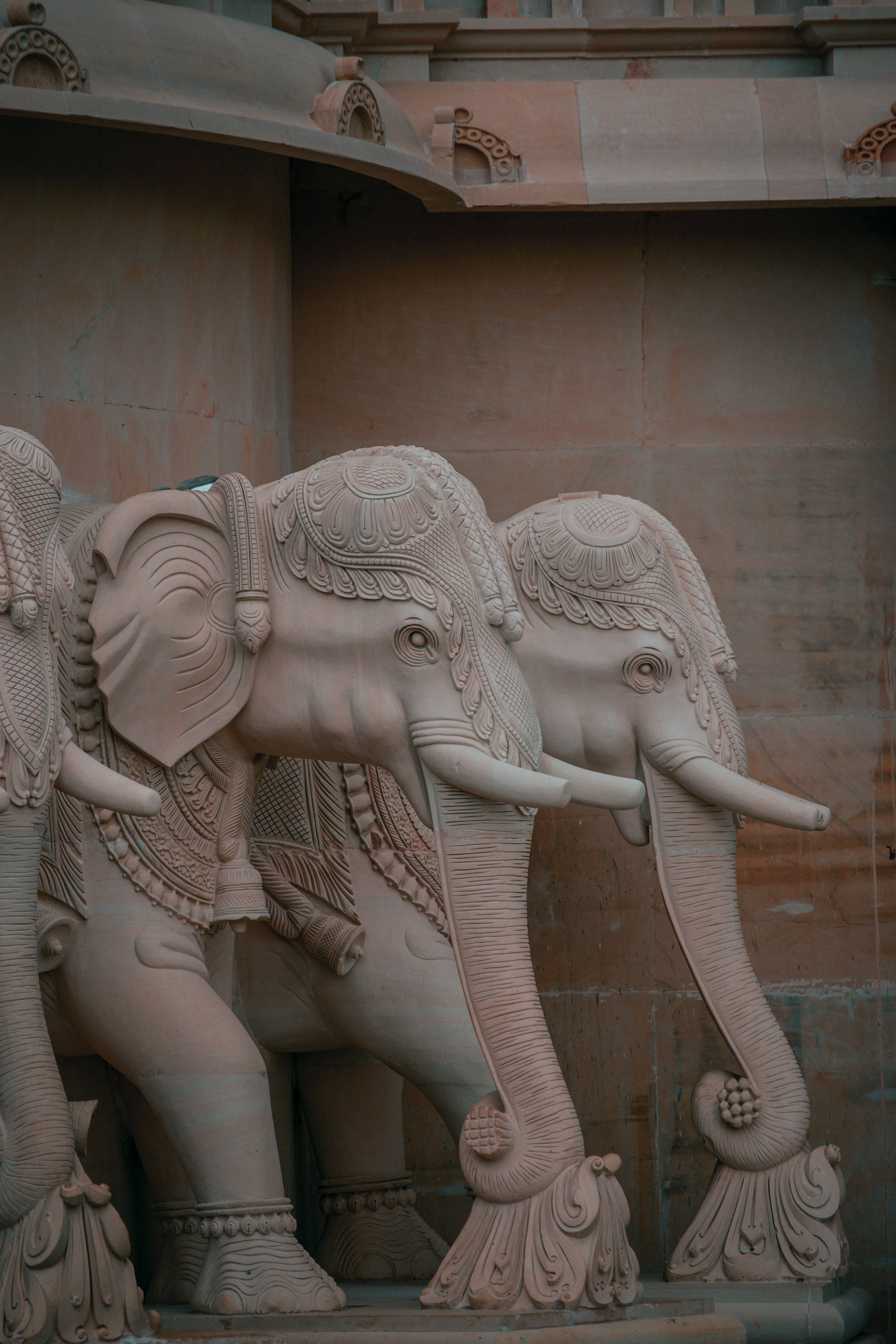 Elephant iPhone 桌布 壁紙 — 兩尊雕刻精細的石象雄偉地矗立在帶有華麗細節的寺廟式拱門下。
